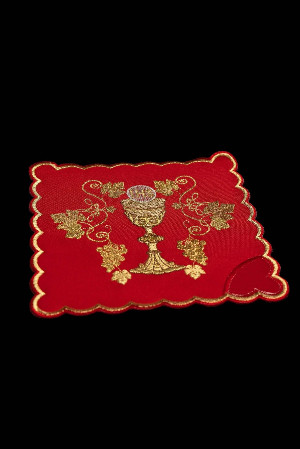 Close-up of a red chalice pall with embroidered chalice, grapes, and IHS motif