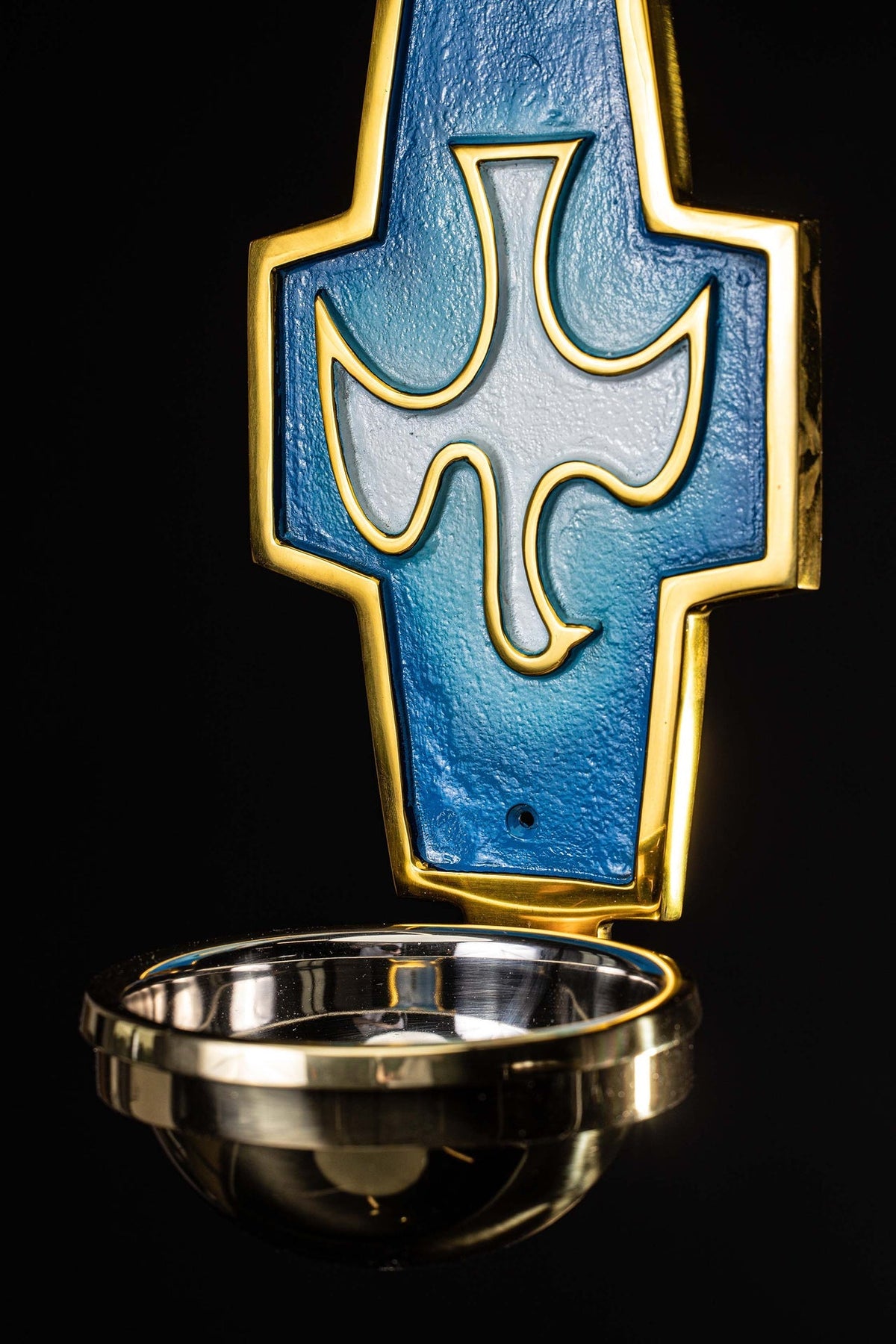 Front detail of the holy water font with brass trim, blue panel, and silver dove