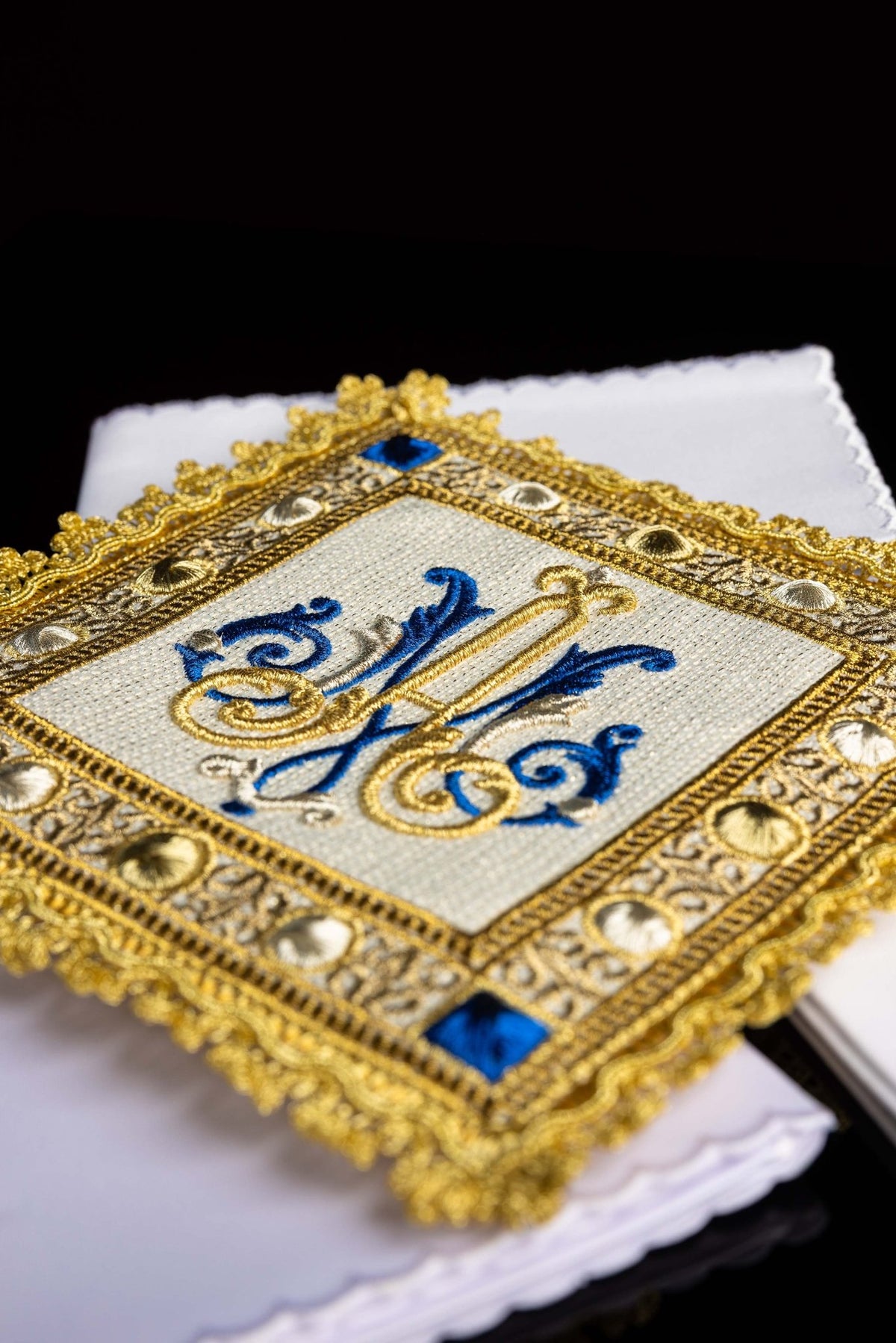 Close-up of the chalice linen set showing blue-and-gold Marian embroidery with jeweled gold border