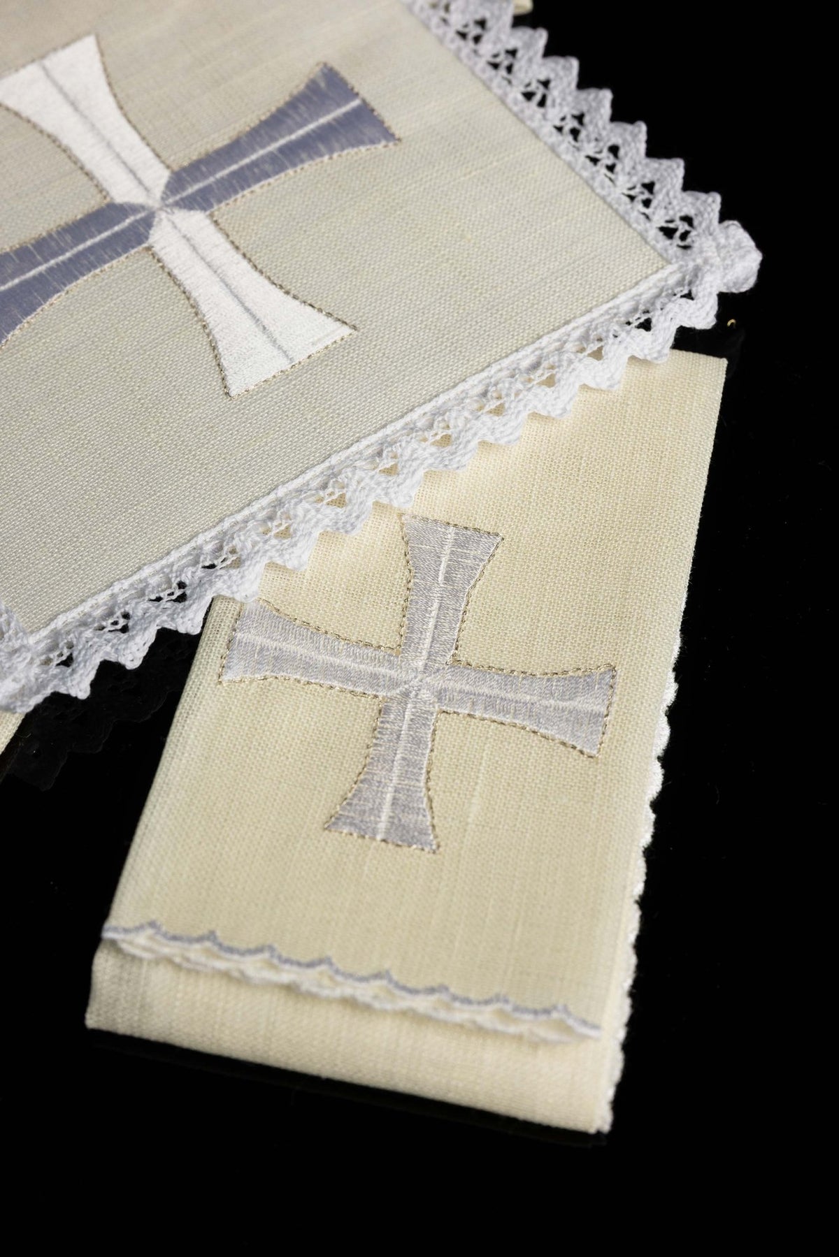 Detail view of chalice linens with delicate cross embroidery, cream linen and white and silver cross
