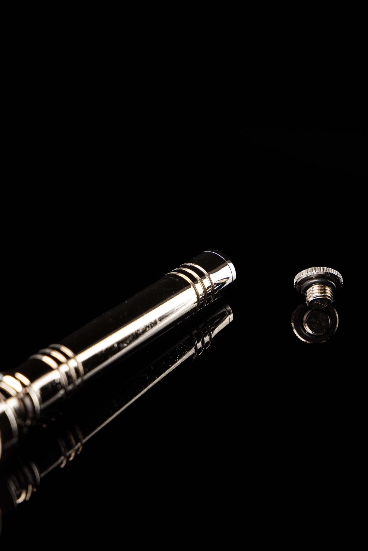 Close-up of the aspergillum showing its ringed handle and polished metal end cap