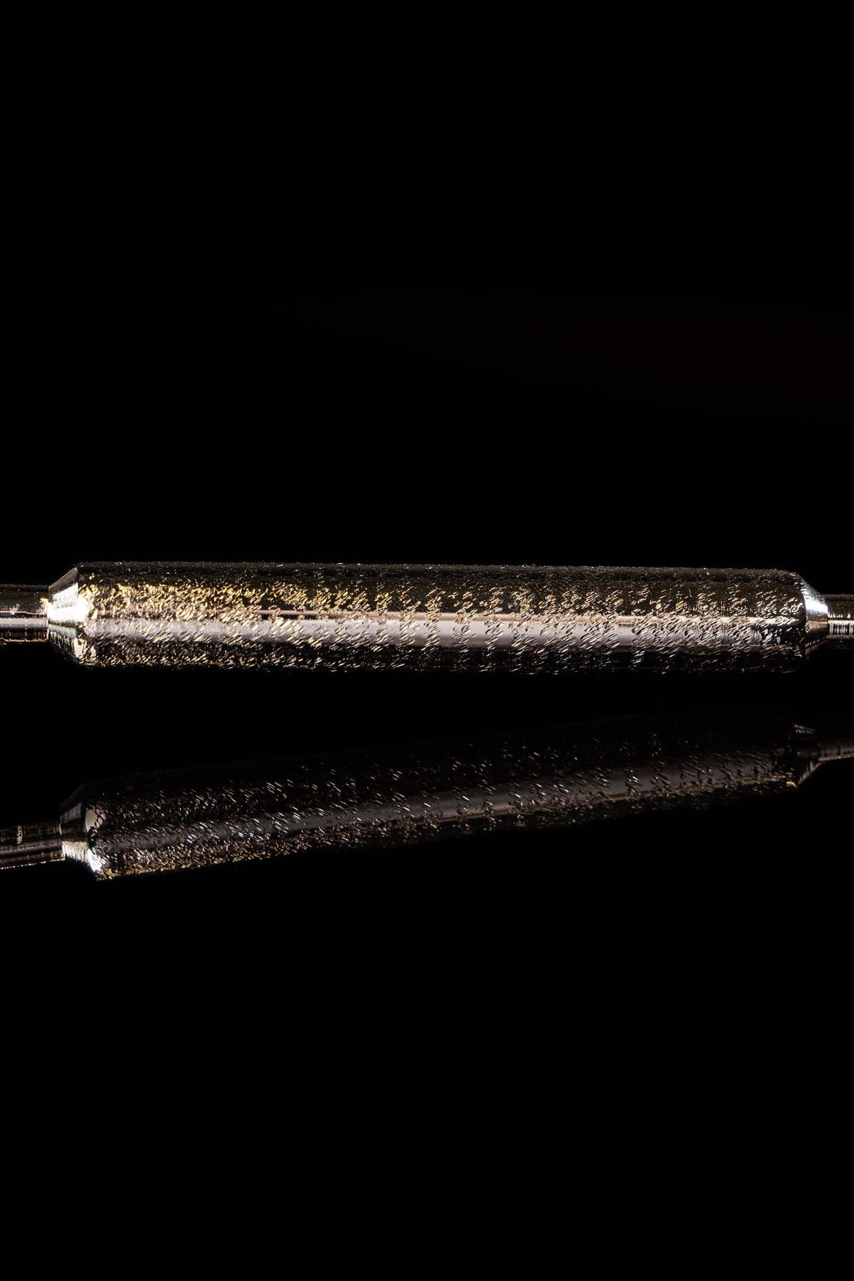 Close-up of a metal aspergillum handle with a textured silver metal grip