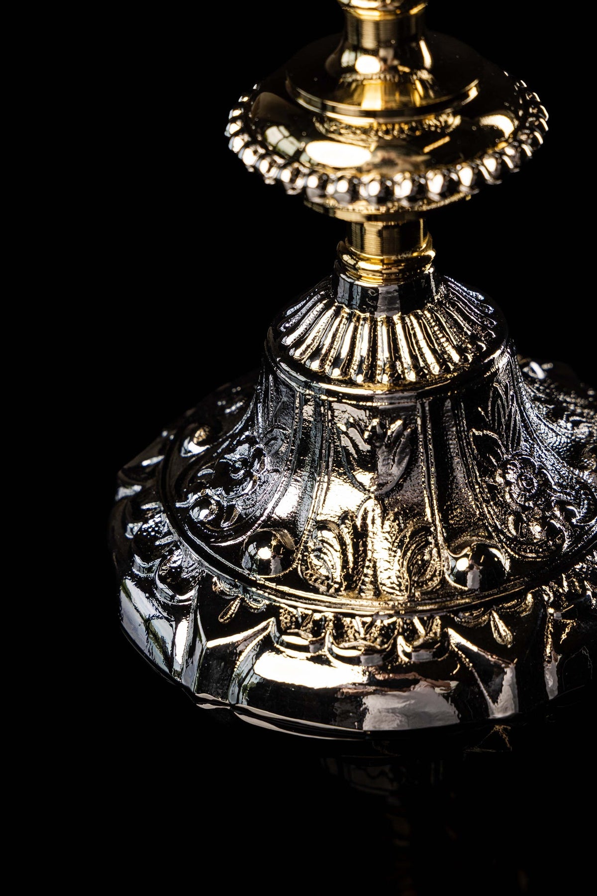 Close-up of the chalice base showing ornate floral relief and alternating gold and silver plating