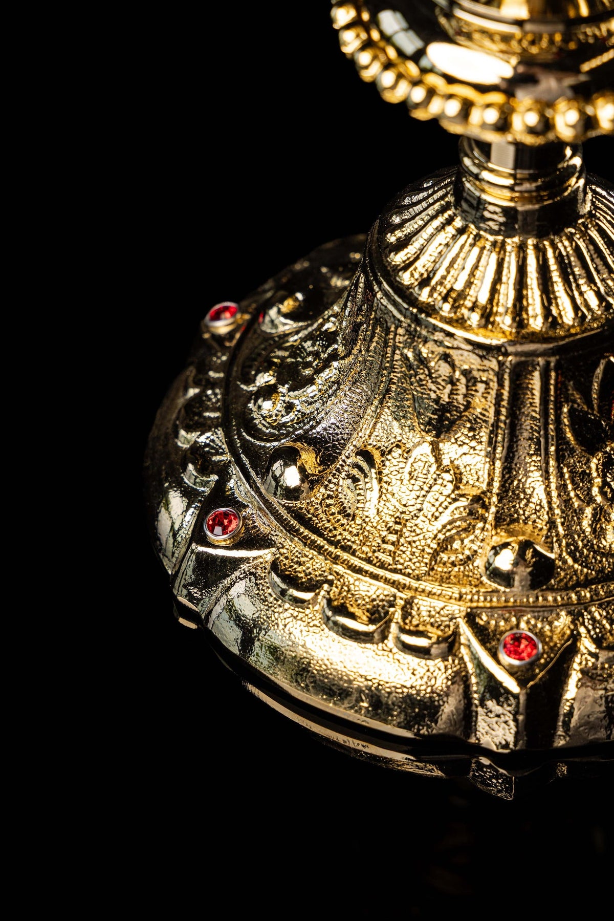 Close-up of the gold-plated chalice base with ornate relief and imitation rubies