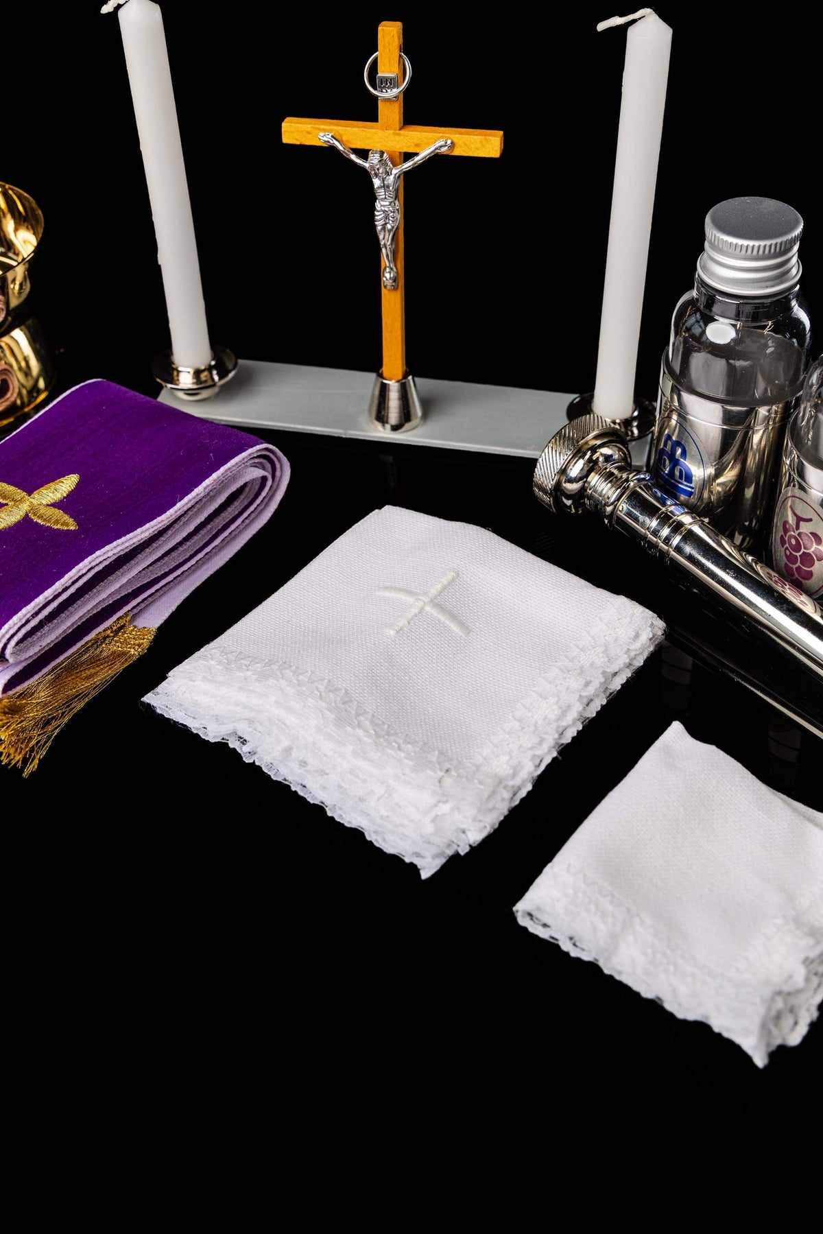 Liturgical equipment suitcase contents including candles, crucifix, purple linen and white cloths