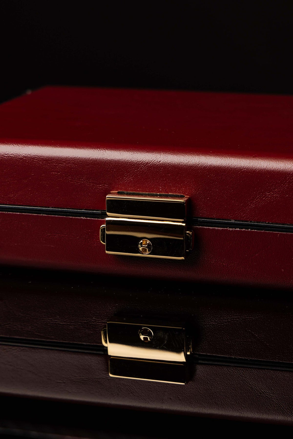 Close-up of liturgical equipment suitcase showing burgundy hard shell and gold clasp