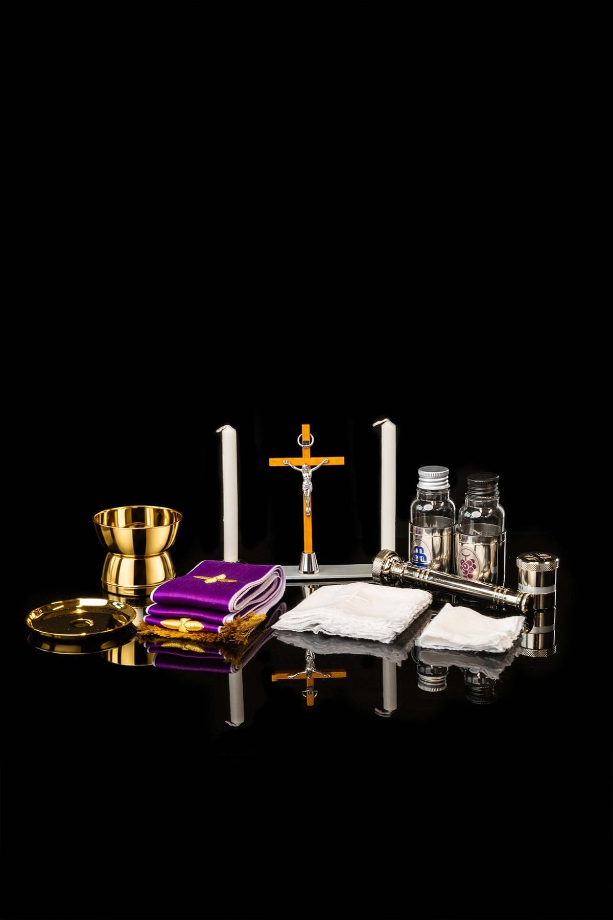 Open equipment suitcase showing gold vessels, candles, crucifix and purple linens