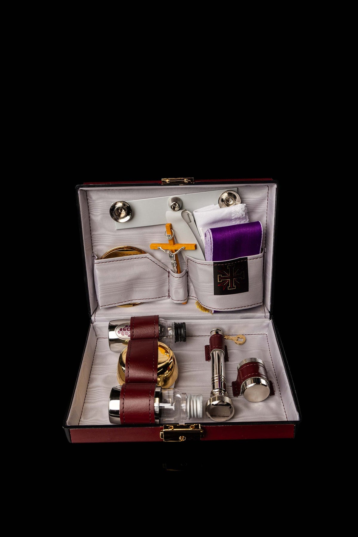 Open hard-shell equipment suitcase with fitted compartments and liturgical accessories