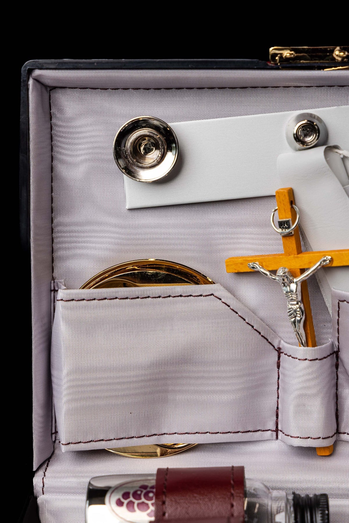 Close-up of equipment suitcase interior with crucifix, gold vessel and snap fasteners