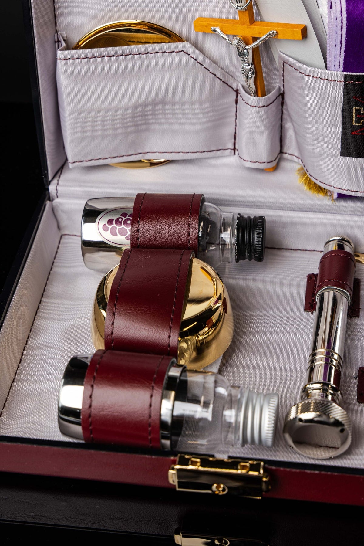 Close-up of equipment suitcase compartments with gold vessel and crucifix