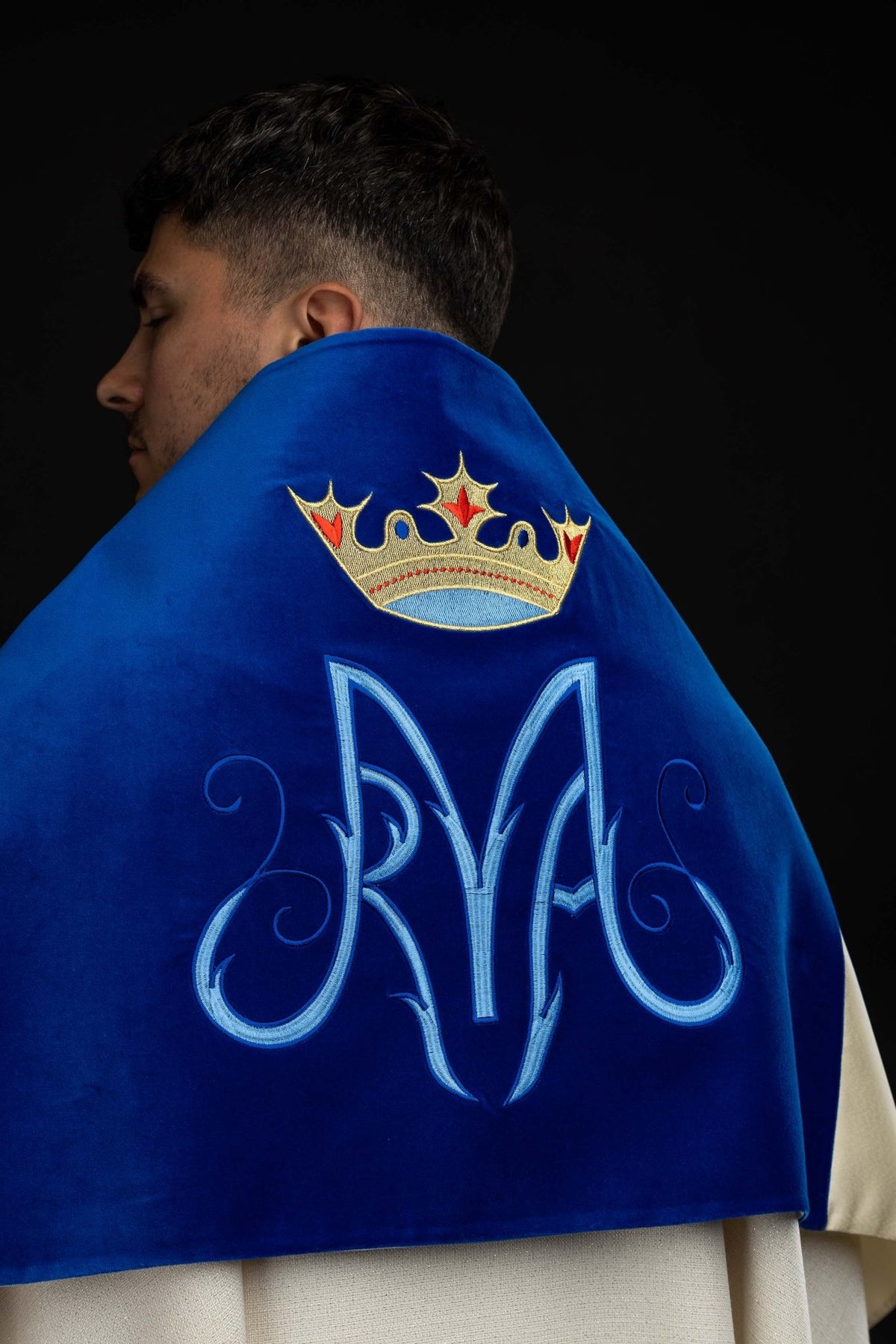 Worn back view of an ecru humeral veil with Marian embroidery on blue velvet