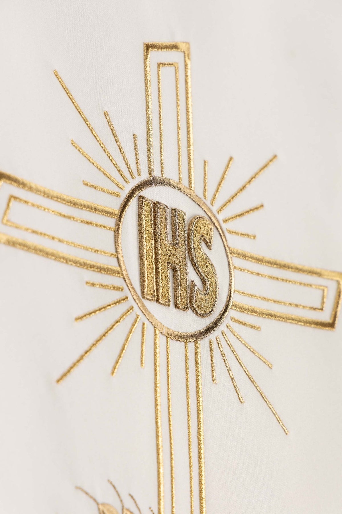 Detailed close-up of the ecru lectern cloth showing gold cross rays and IHS monogram
