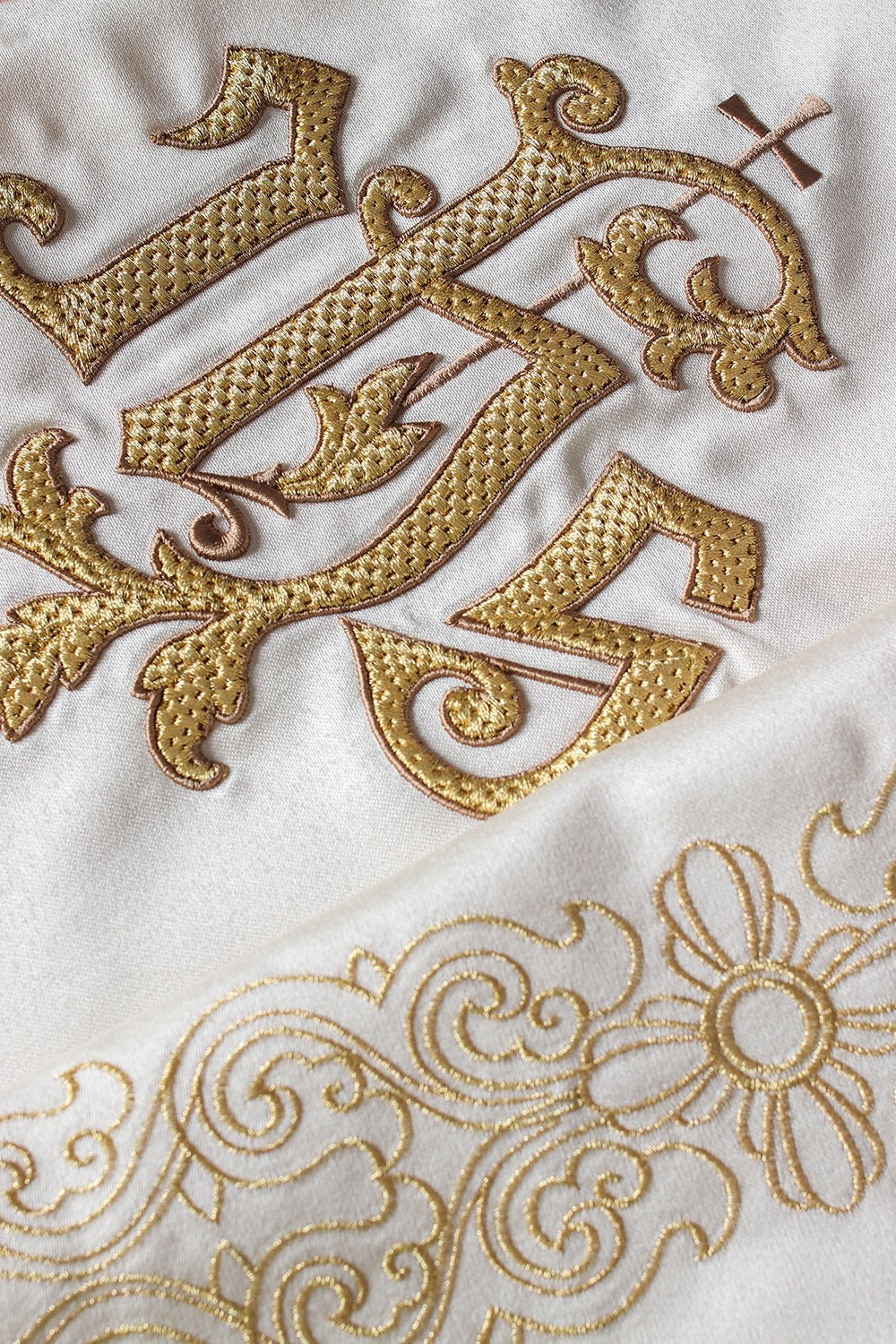 Close-up of the humeral veil showing gold IHS embroidery and ornate floral trim