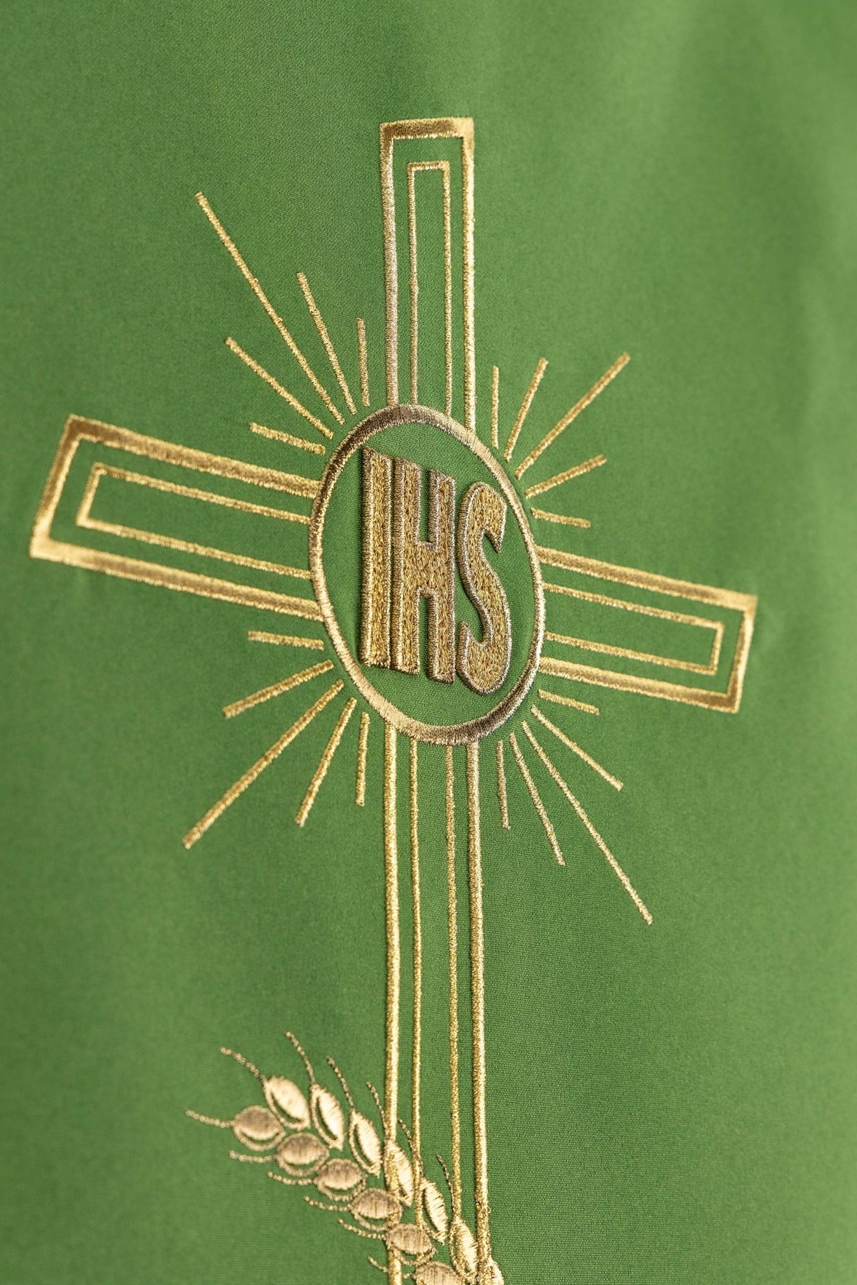 Close-up of the green lectern cloth showing gold embroidered cross, IHS monogram, and rays