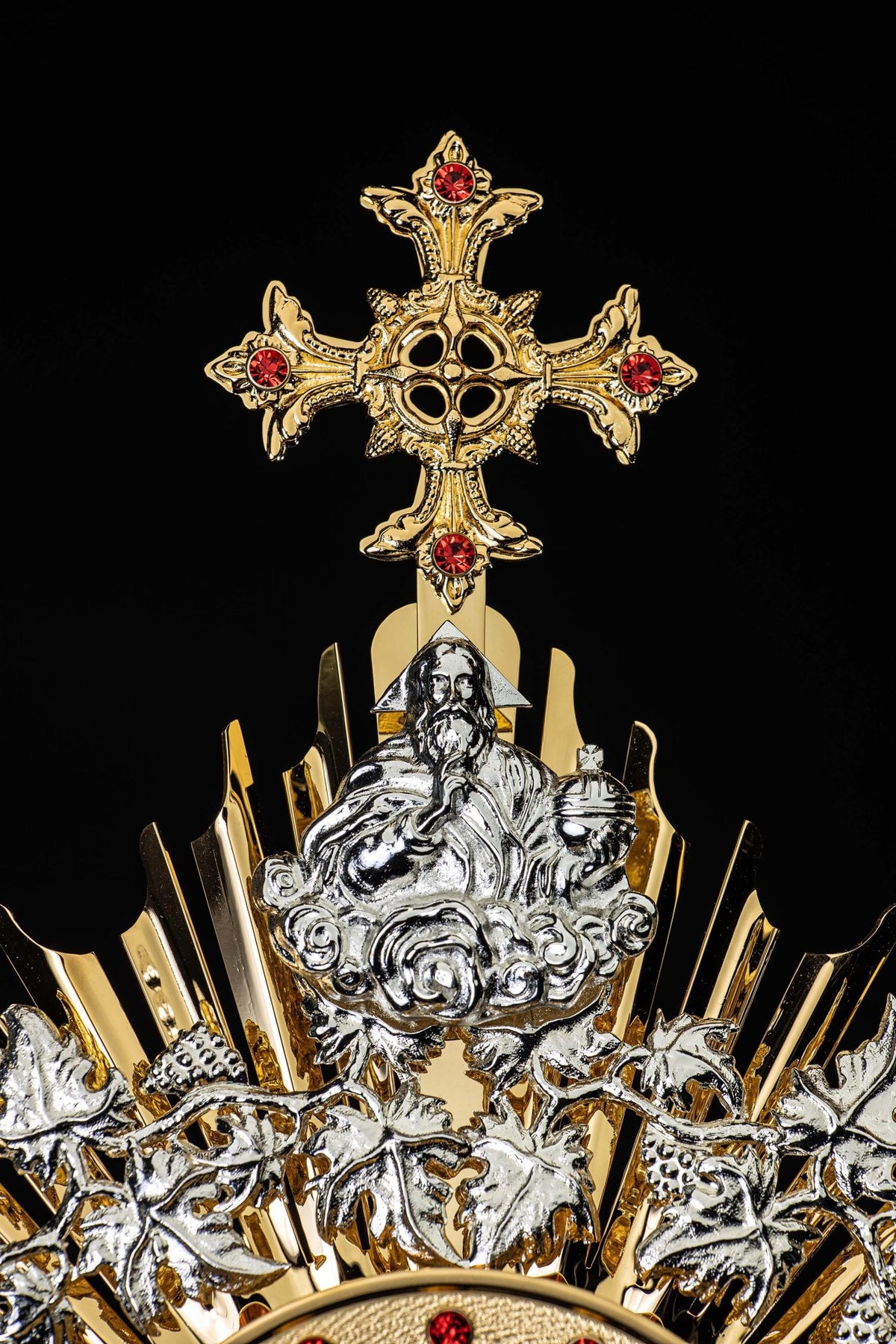 Close-up of the monstrance showing a ruby-set cross and silver-tone Christ figure