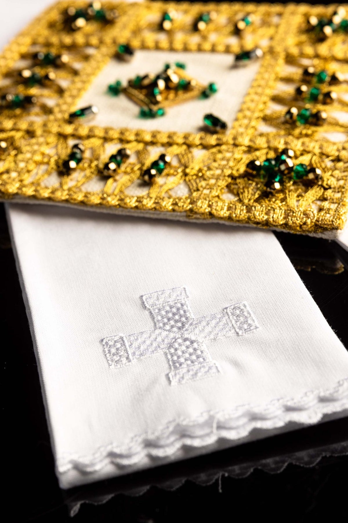 Detail view of the altar linen set's white linen with embroidered cross and scalloped edge