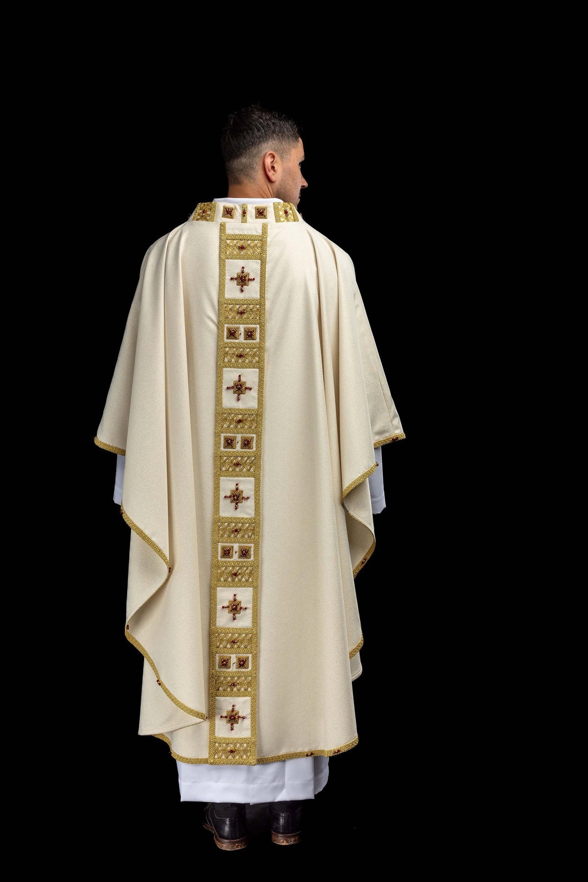 Back view of a white handmade chasuble with a gold-trimmed panel and red stone crosses