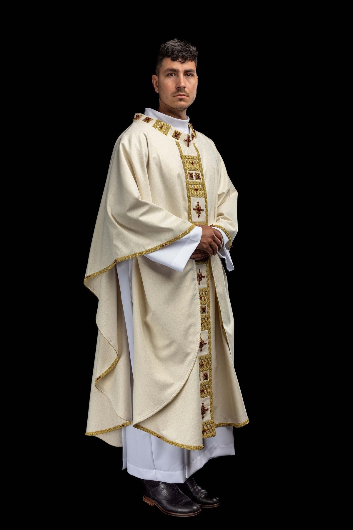 Front view of a white handmade chasuble with a gold-trimmed panel and red stones