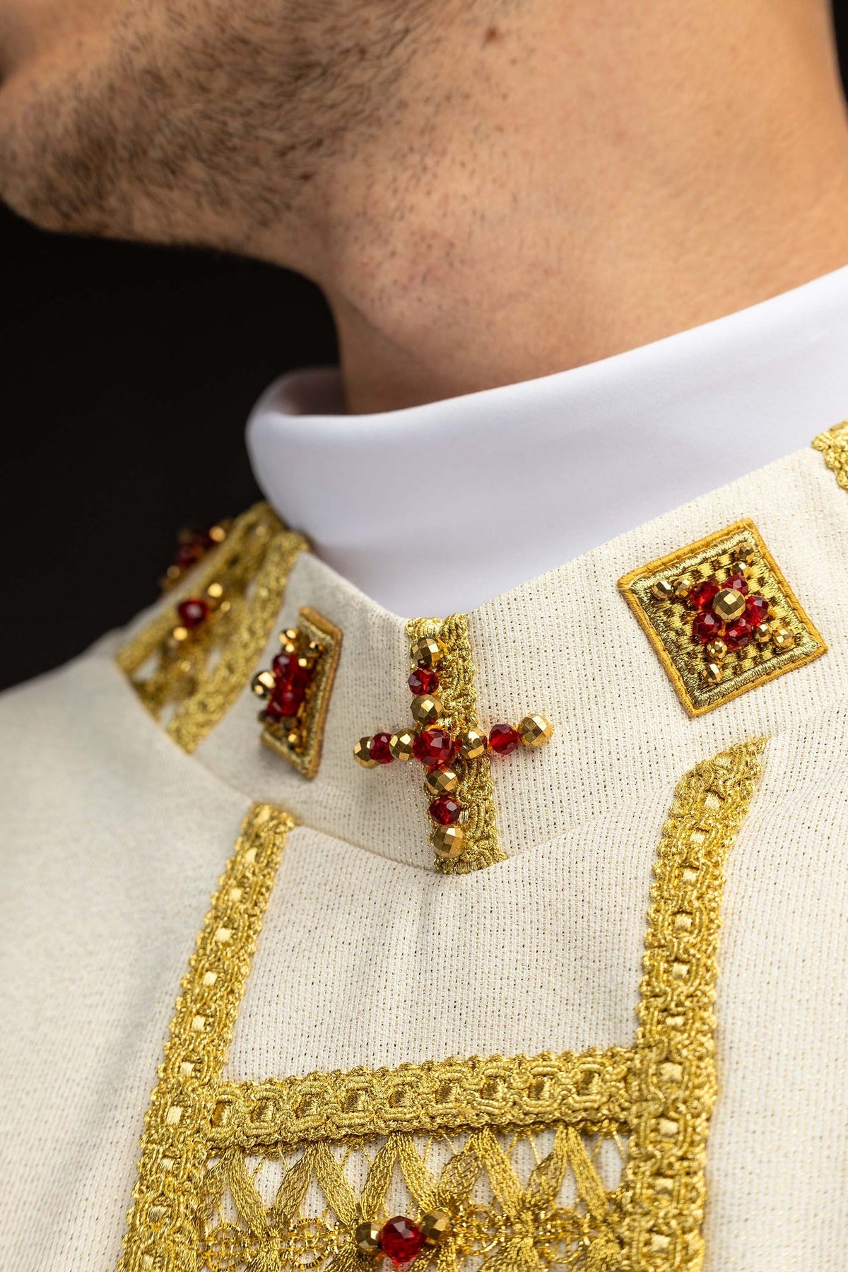 Close-up of the chasuble collar with gold trim and red and gold stone cross