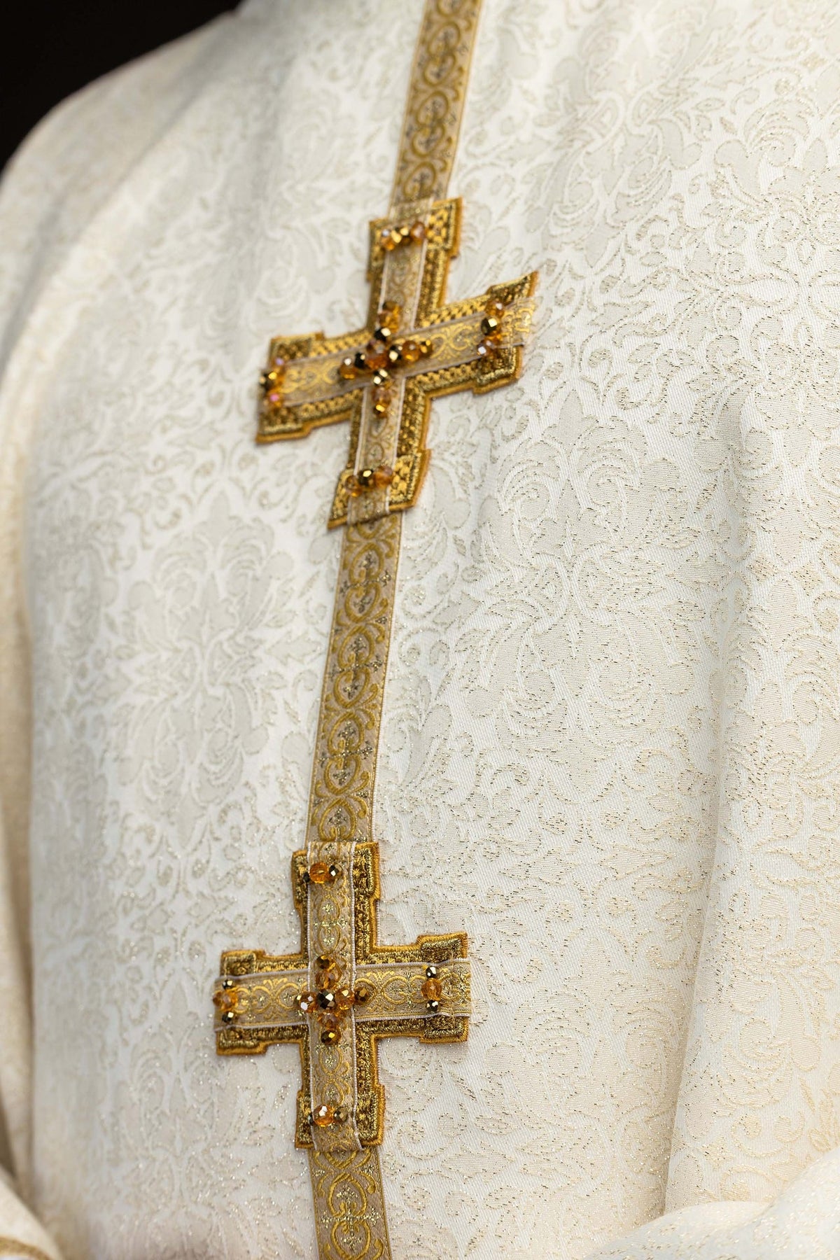 Close-up of two gold crosses with amber stones on the chasuble