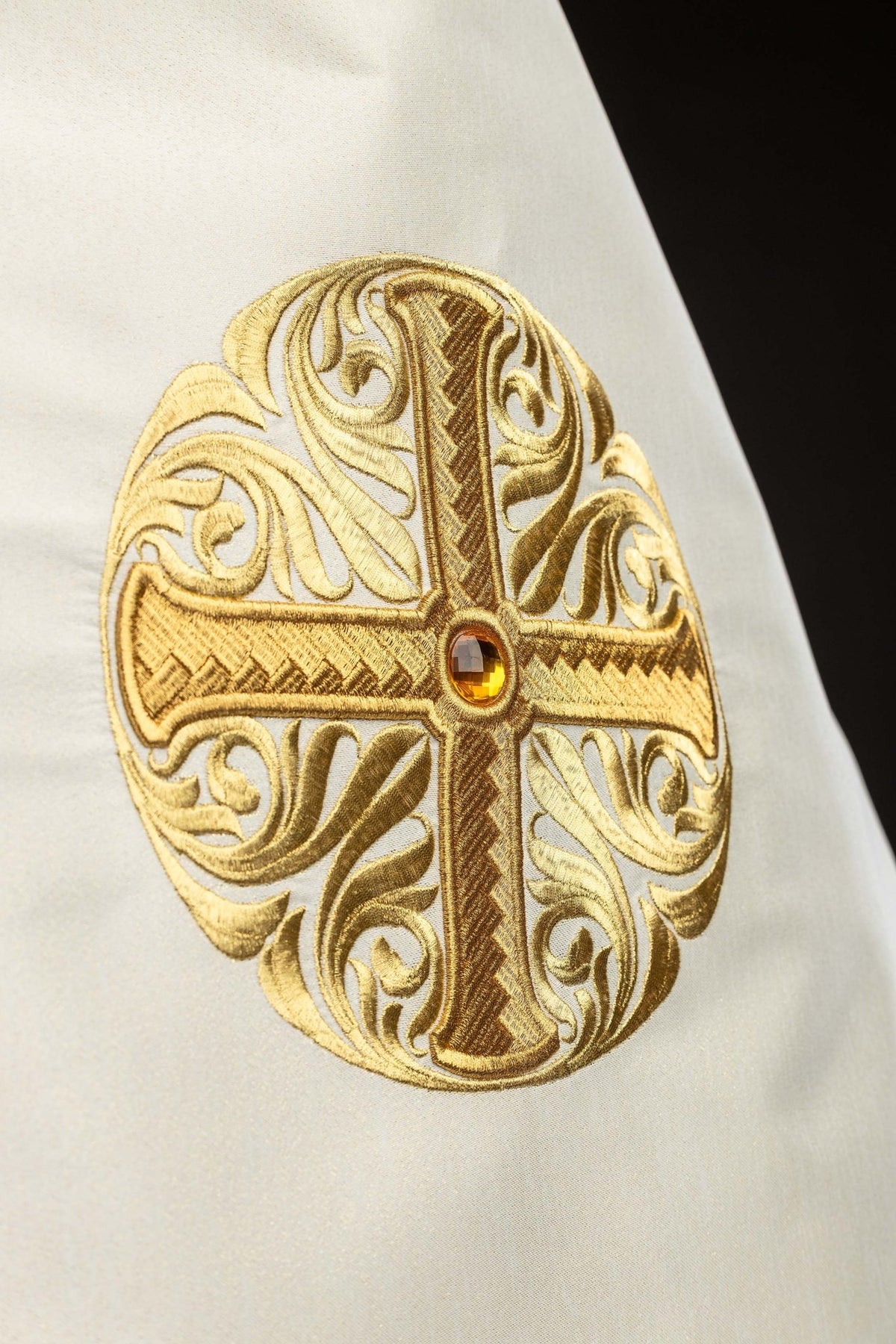 Close-up of the humeral veil's embroidered gold cross with a central decorative stone