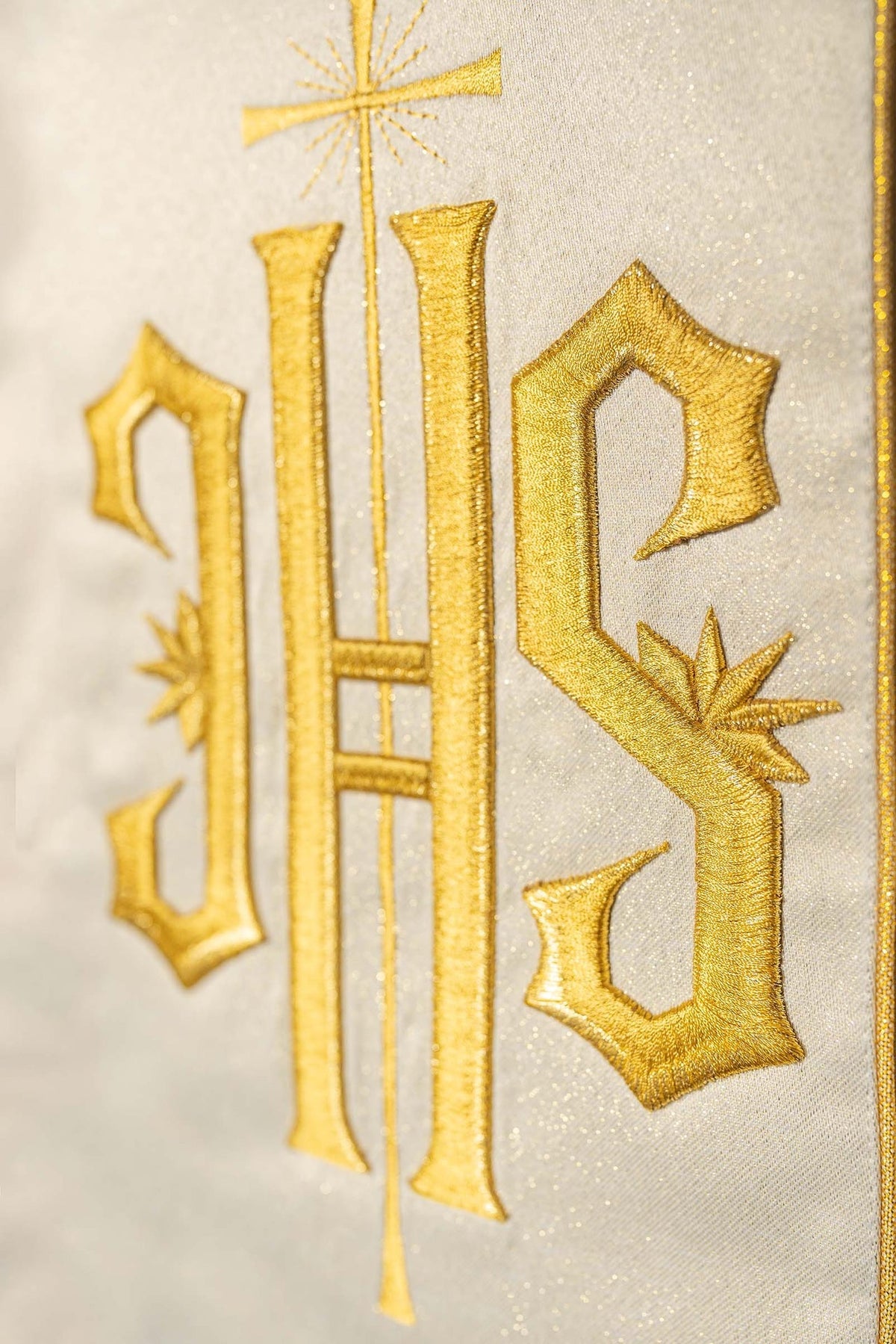 Close-up of the gold chasuble showing embroidered IHS letters and cross