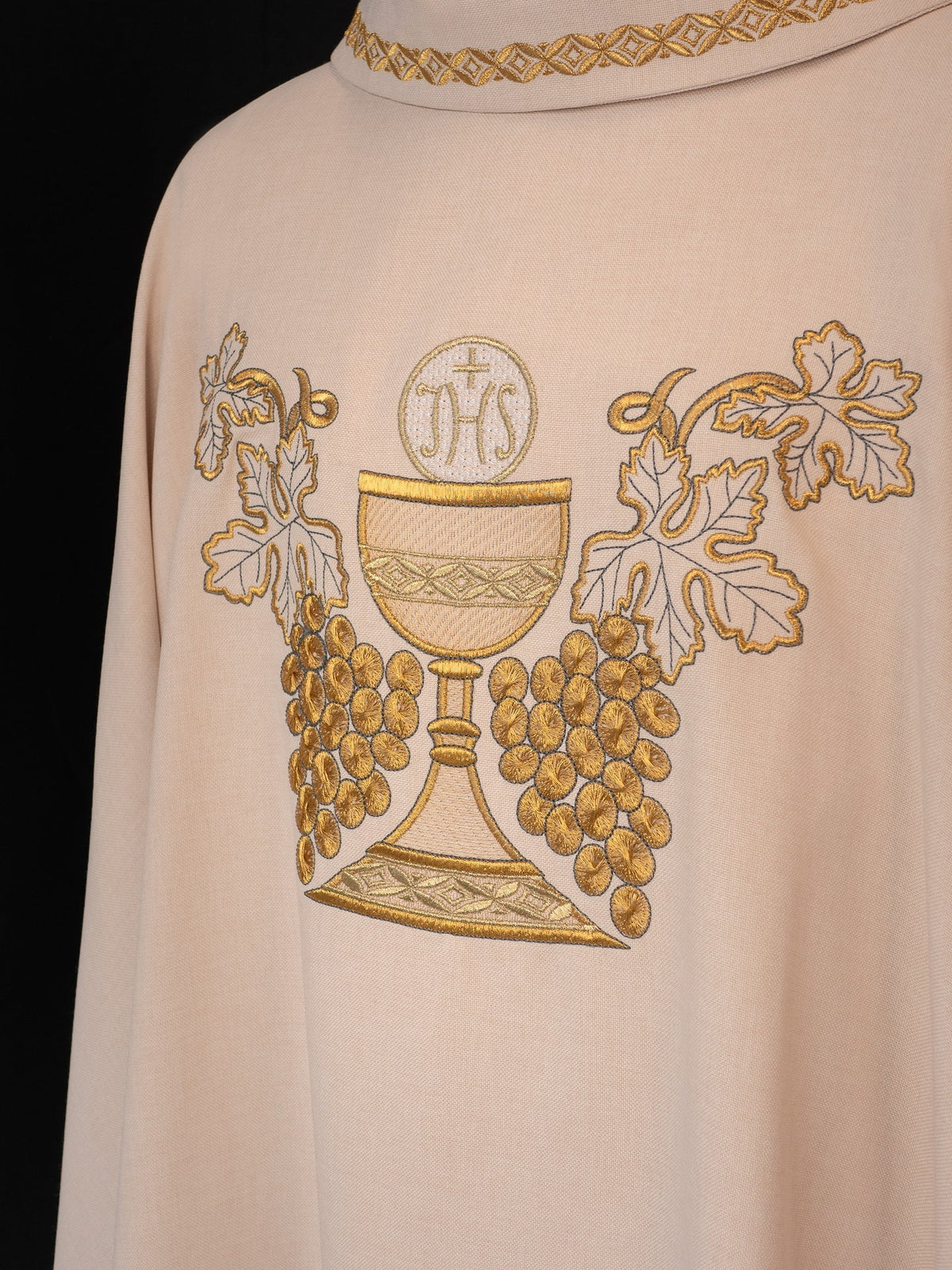 Close-up of the ecru chasuble showing embroidered chalice, IHS, grapes and vine leaves