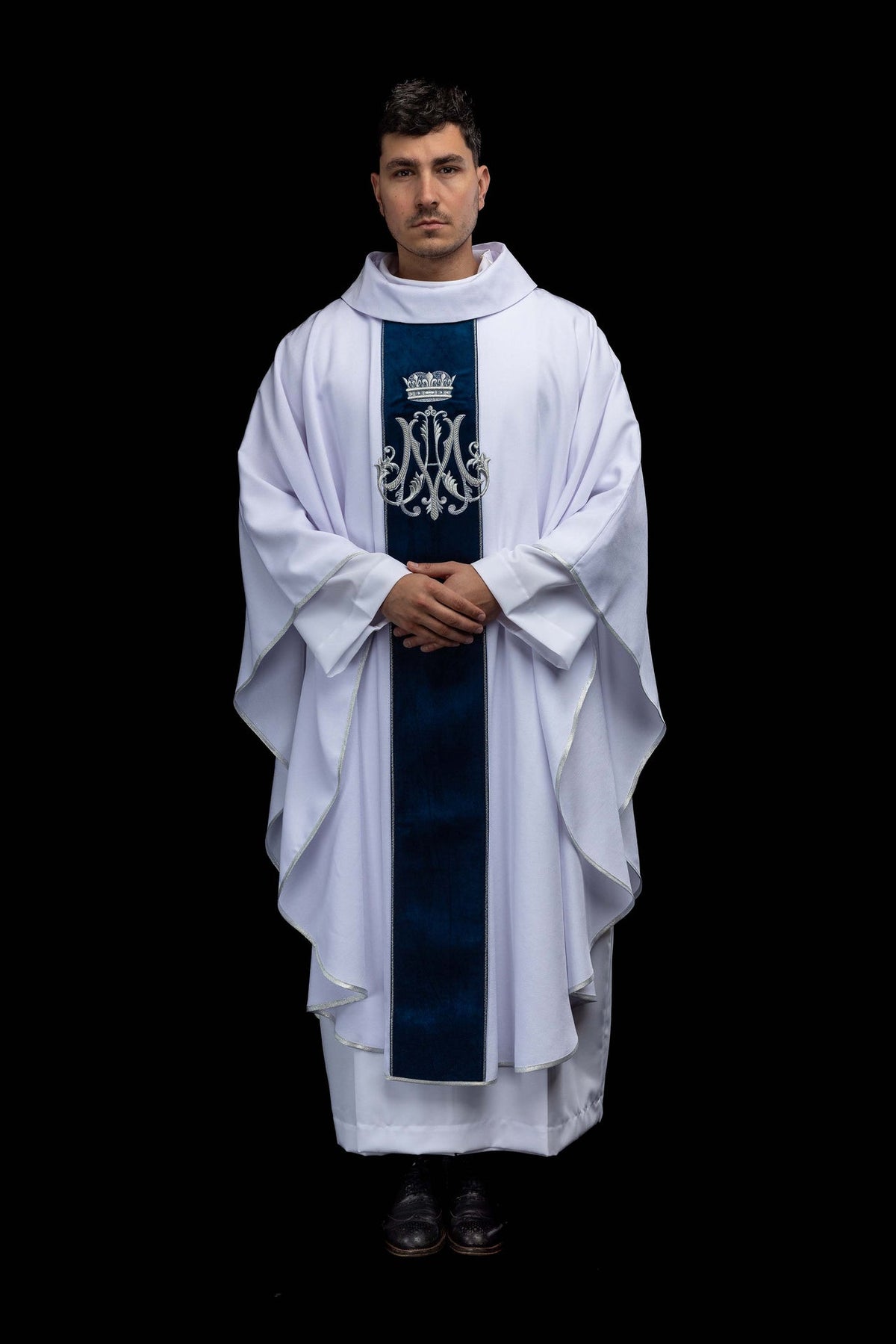 Full front view of the ecru Marian chasuble with silver embroidered monogram and blue velvet orphrey