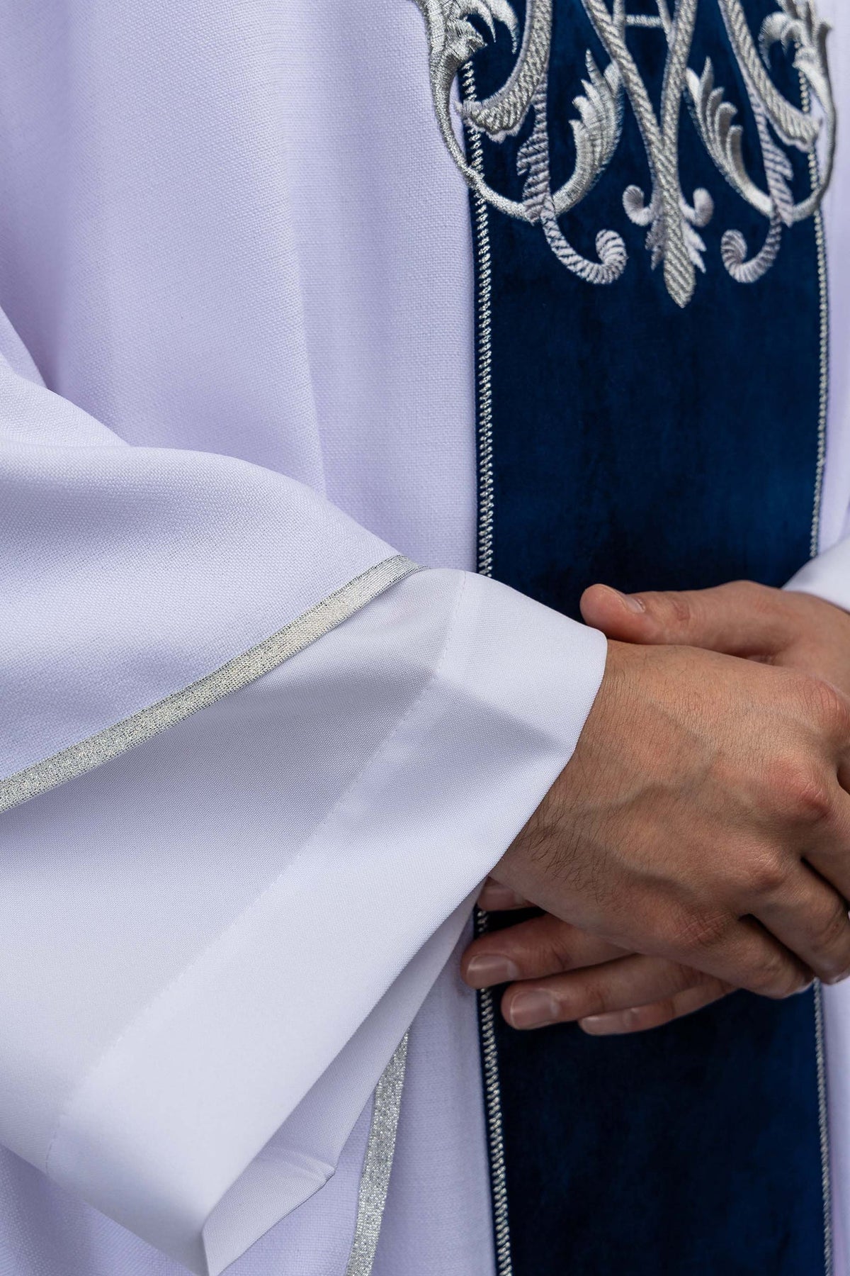 Close-up of the ecru chasuble sleeve showing silver edging and blue velvet orphrey