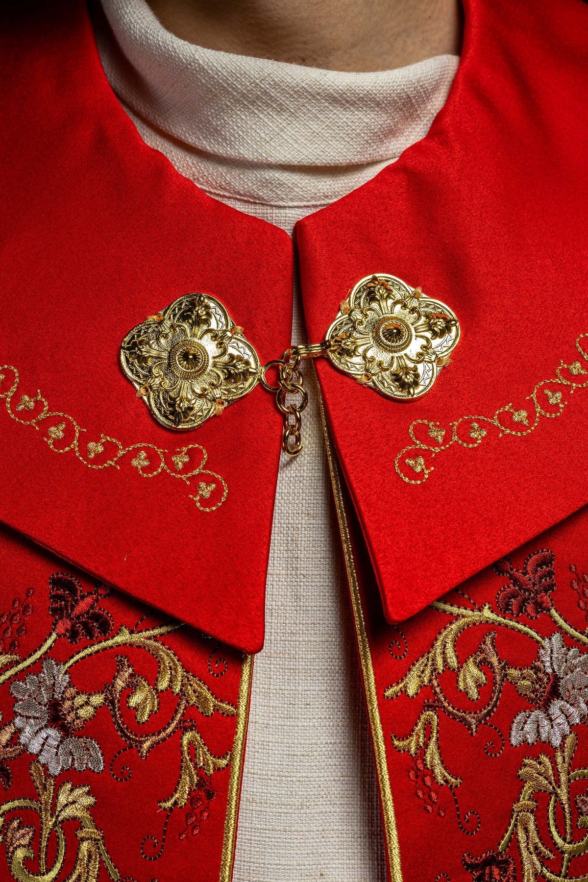 Close-up of red cope clasp with gold floral medallions and embroidered trim
