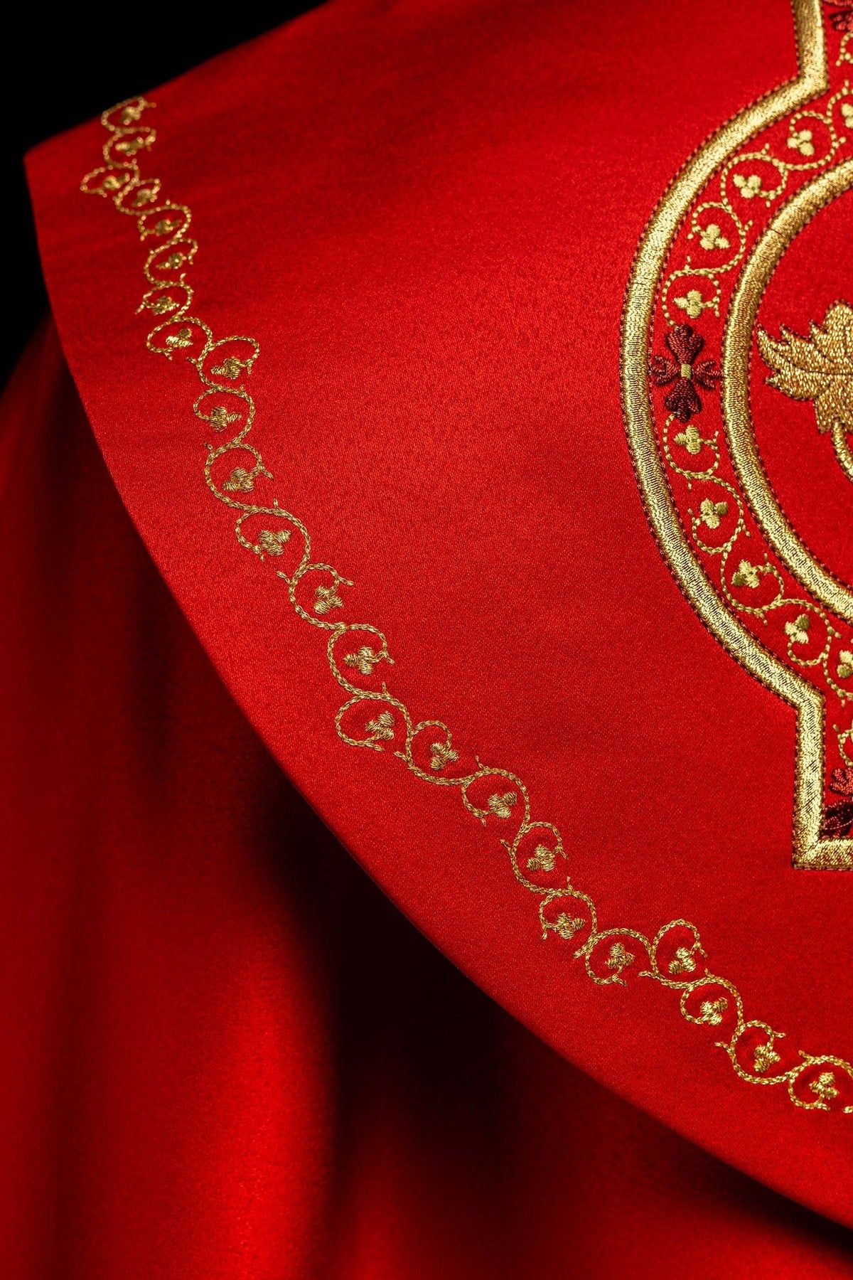 Detail of red cope showing gold scrollwork embroidery and ornate back border