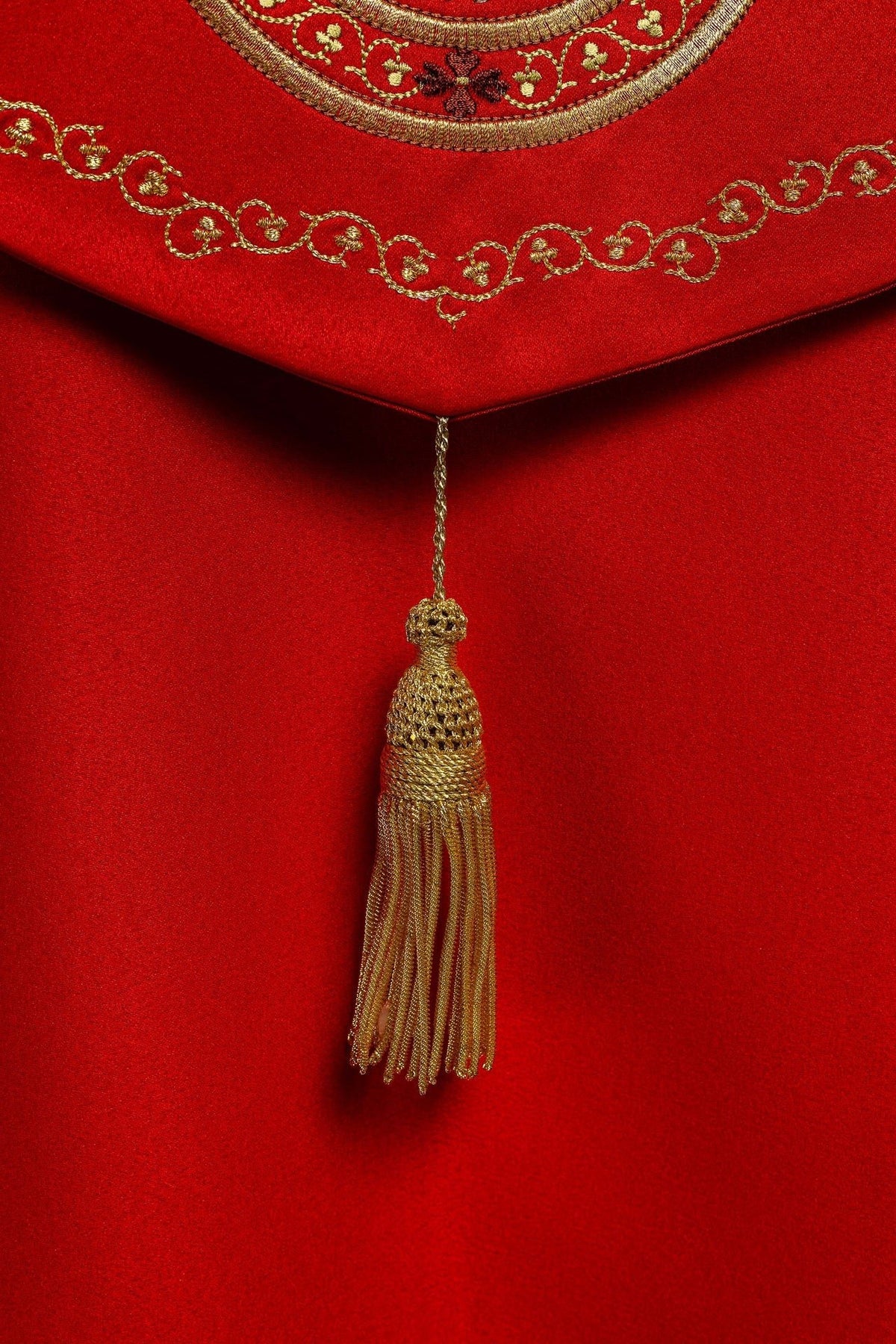 Close-up of red cope hem with gold embroidered scrollwork and floral border