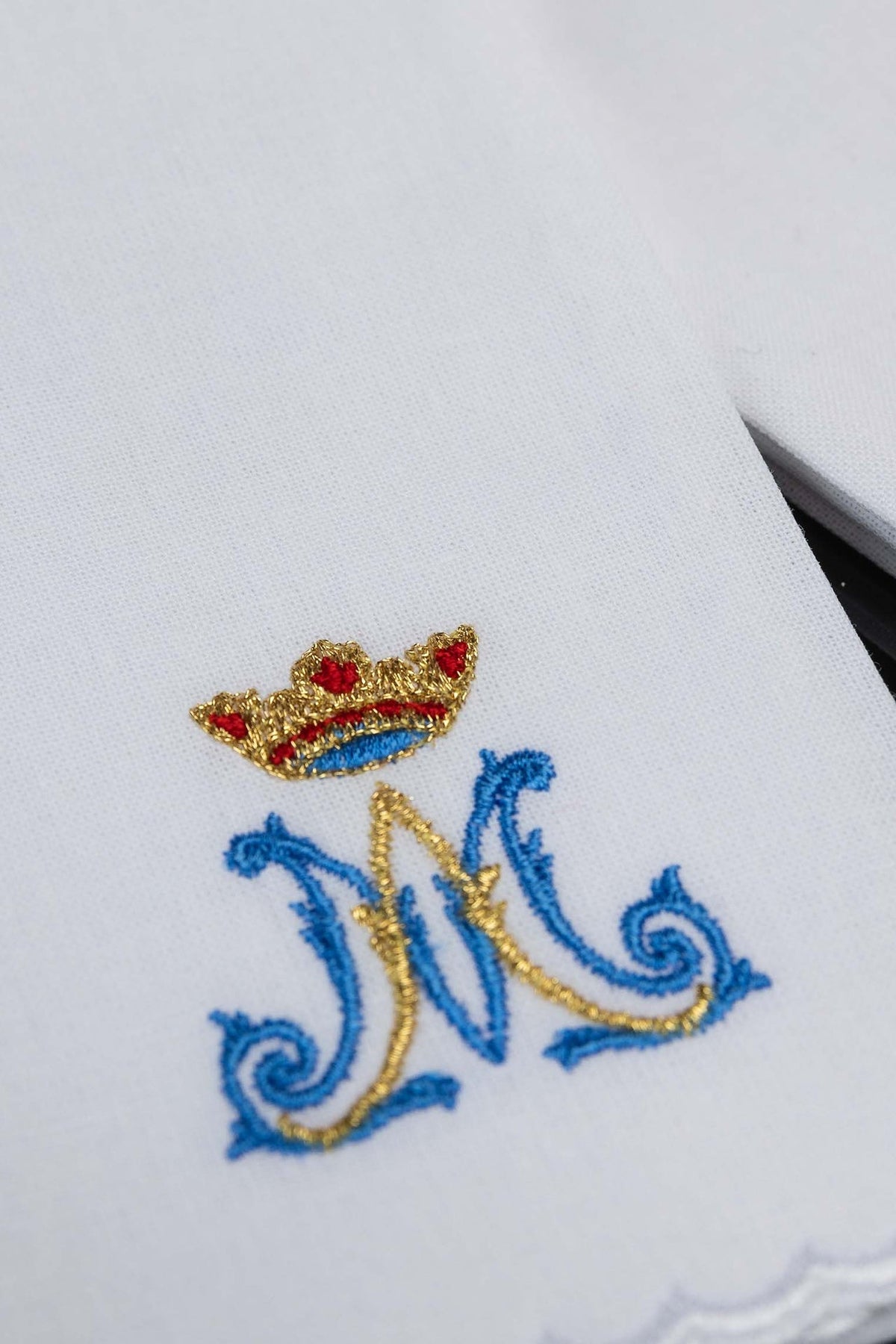 Close-up of a white purificator with blue and gold Marian motif embroidery