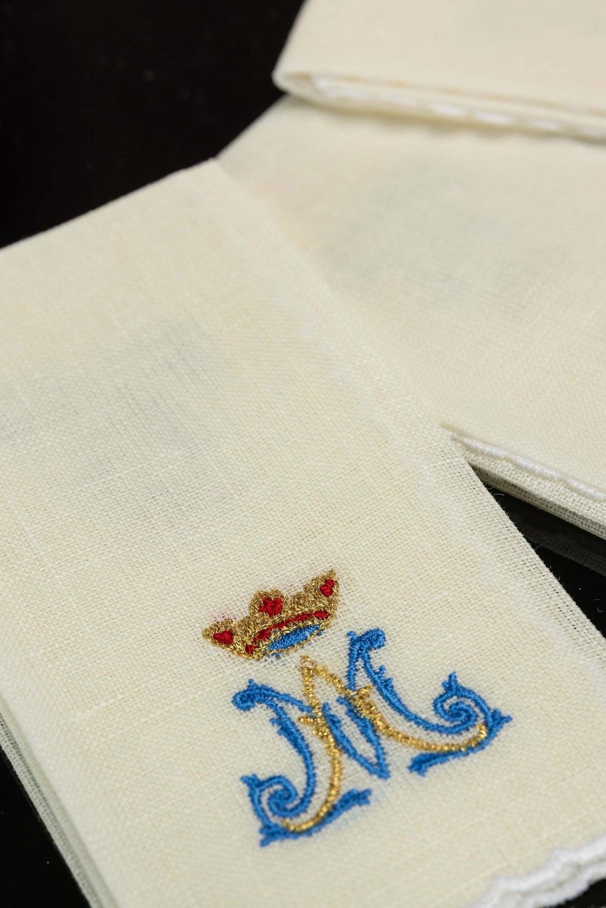 Close-up of linen purificator with blue and gold Marian motif embroidery and crown