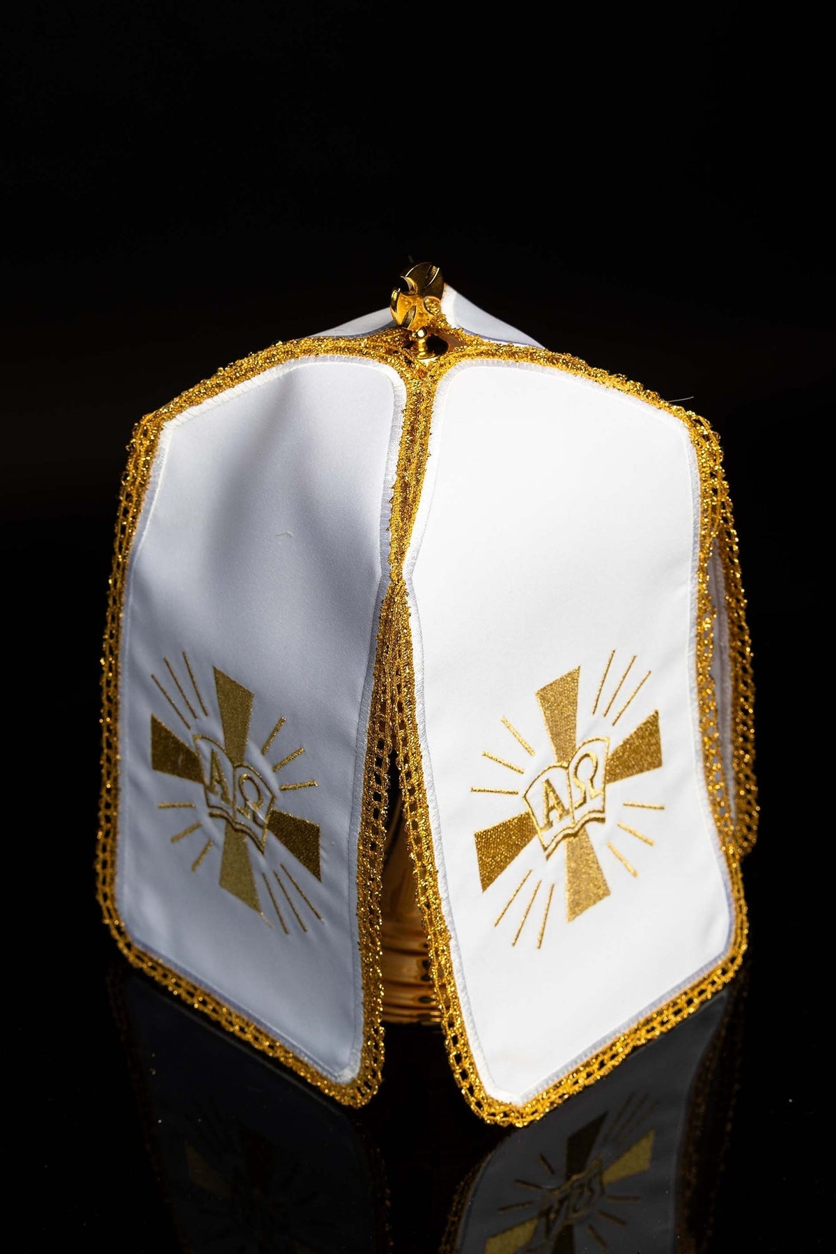 Angled view of ciborium veil showing two white panels with gold Alpha and Omega embroidery