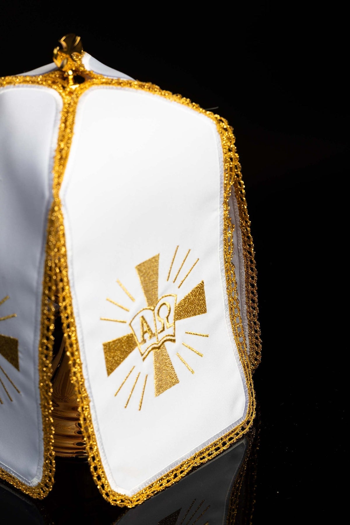 Side view of ciborium veil showing white fabric, gold trim and Alpha and Omega embroidery