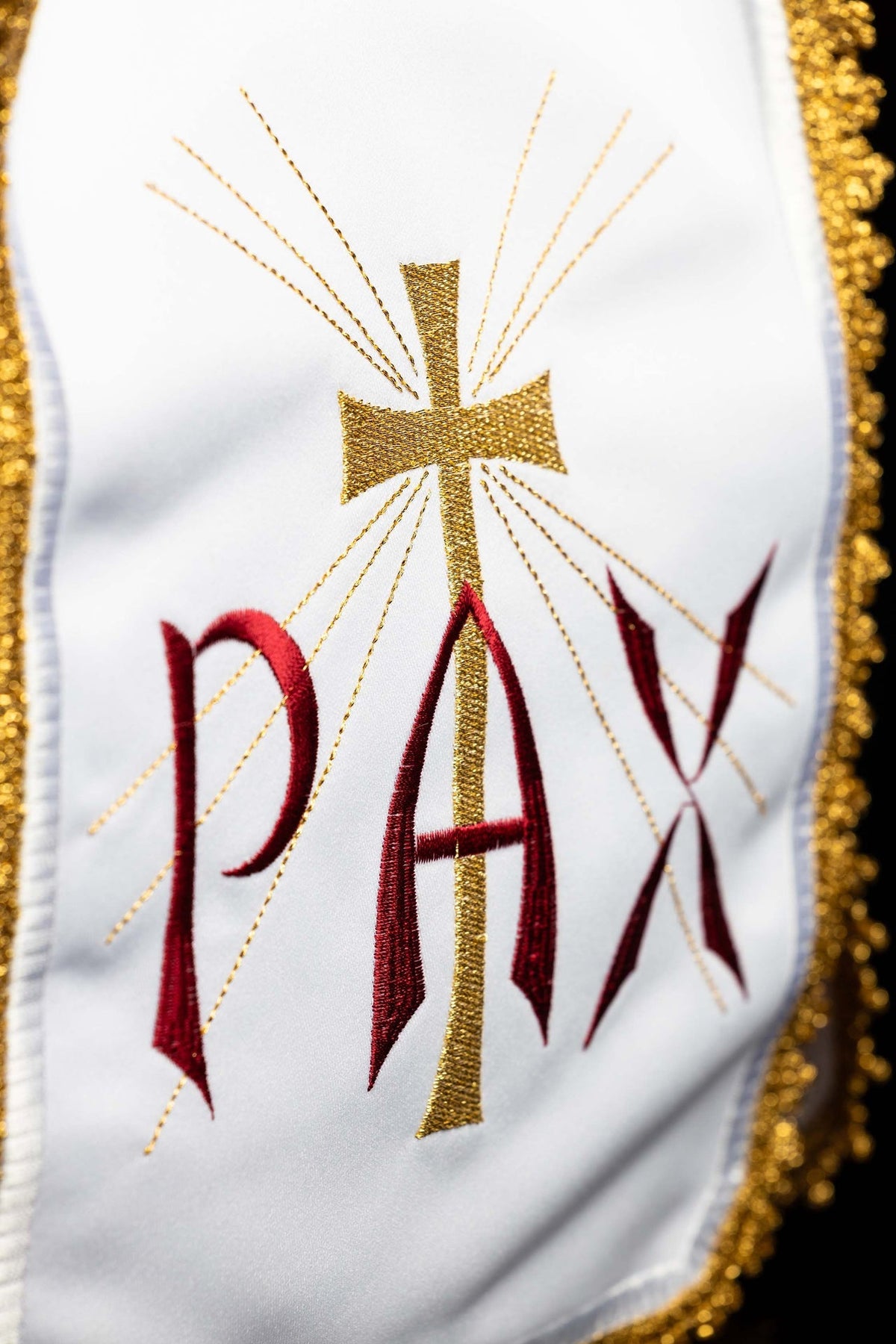 Close-up of the ciborium veil showing a gold cross with radiant rays and red PAX embroidery