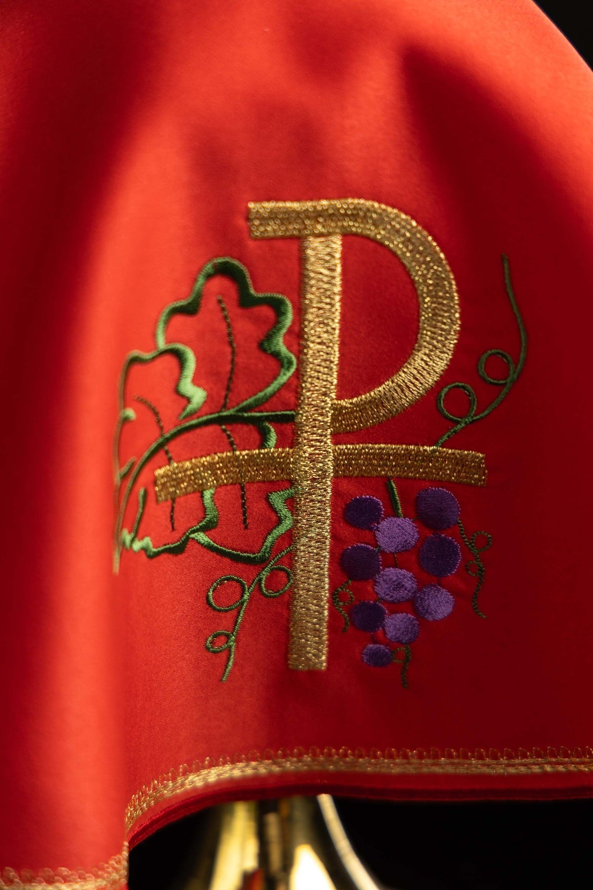 Close-up of a red ciborium veil with gold PAX, grapes and leafy embroidery