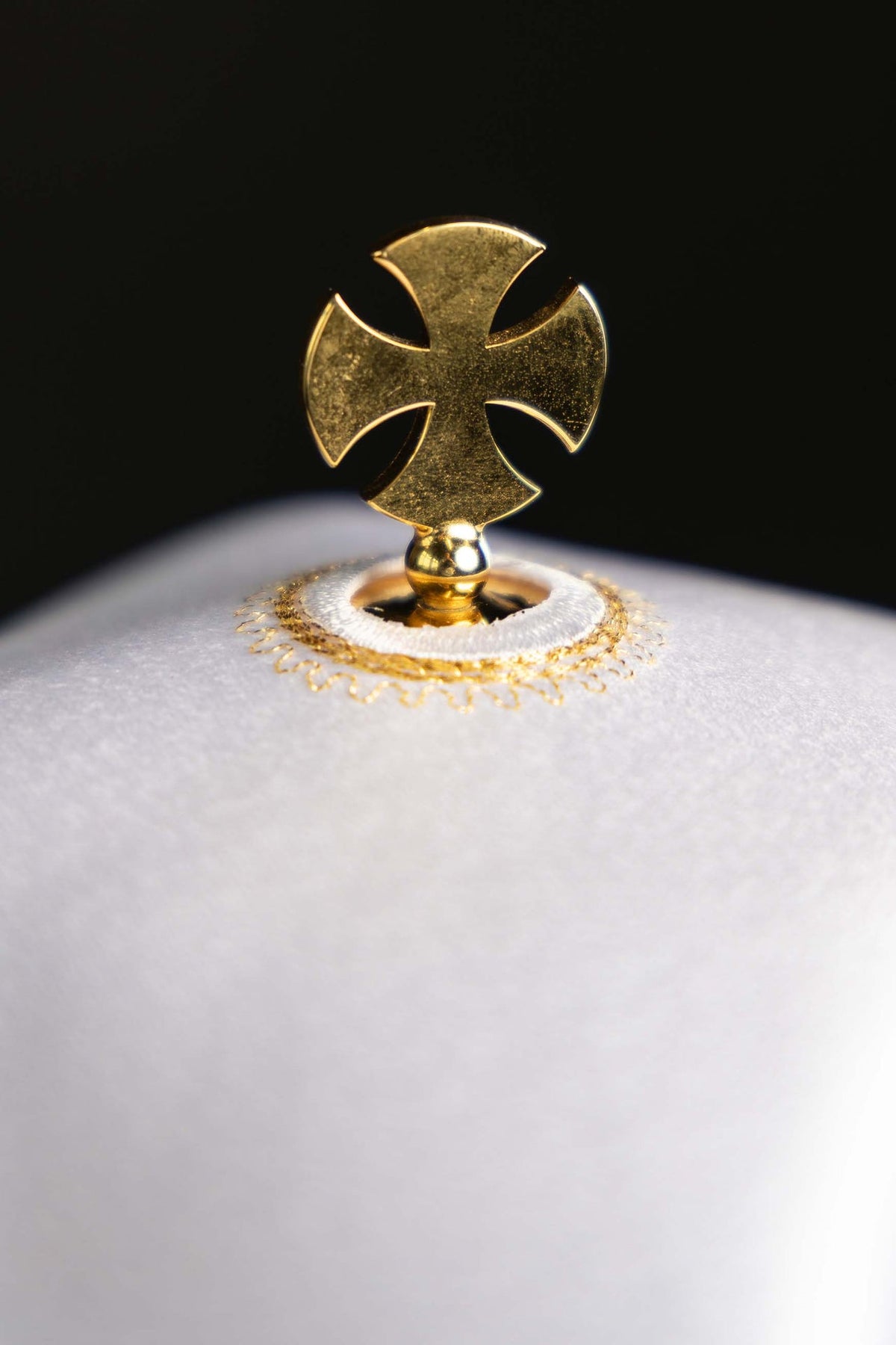 Close-up of the gold cross finial on the white ciborium veil
