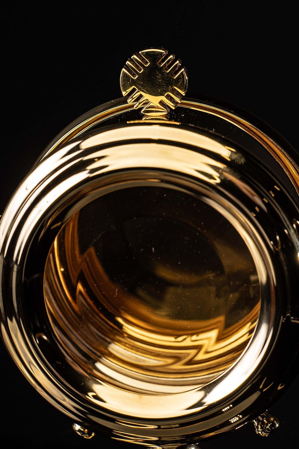 Close-up of the brass custodia showing the cross finial and polished circular frame