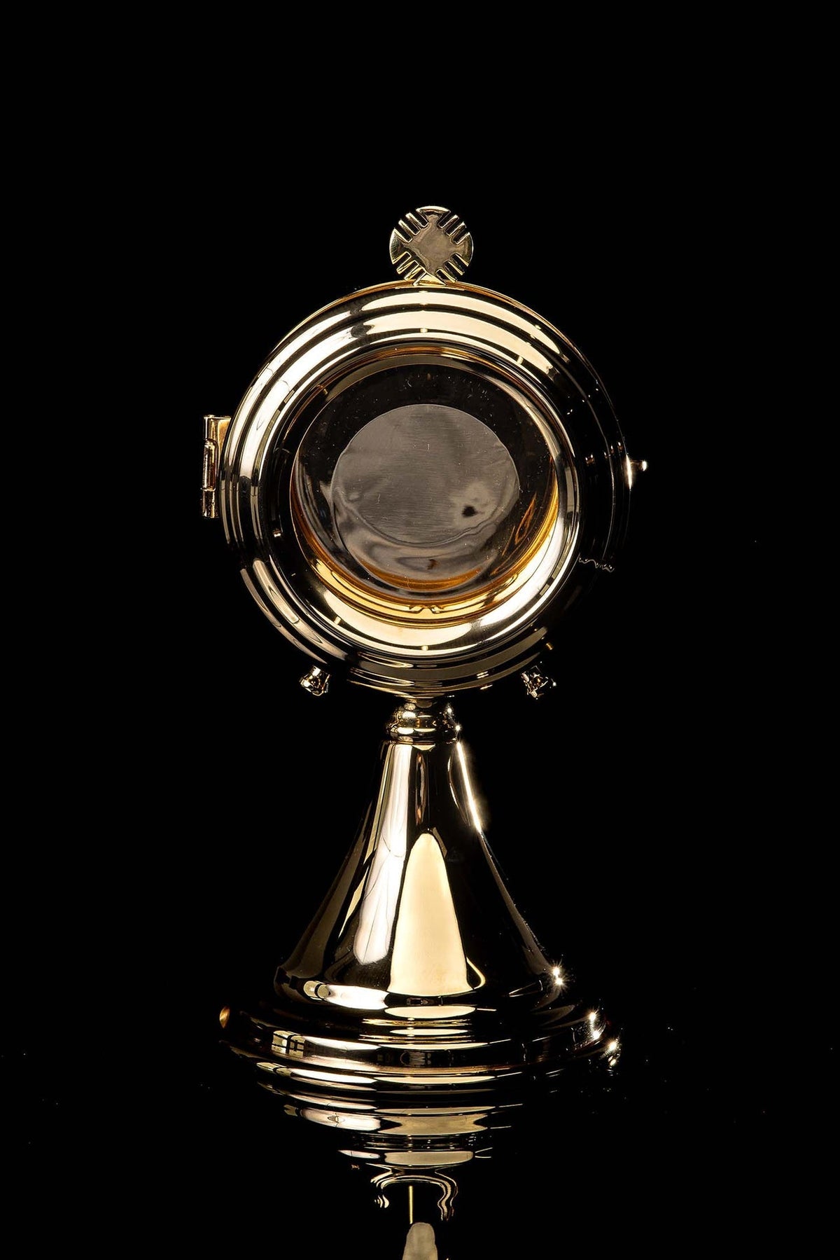 Back view of the brass custodia showing its plain circular center and cross finial