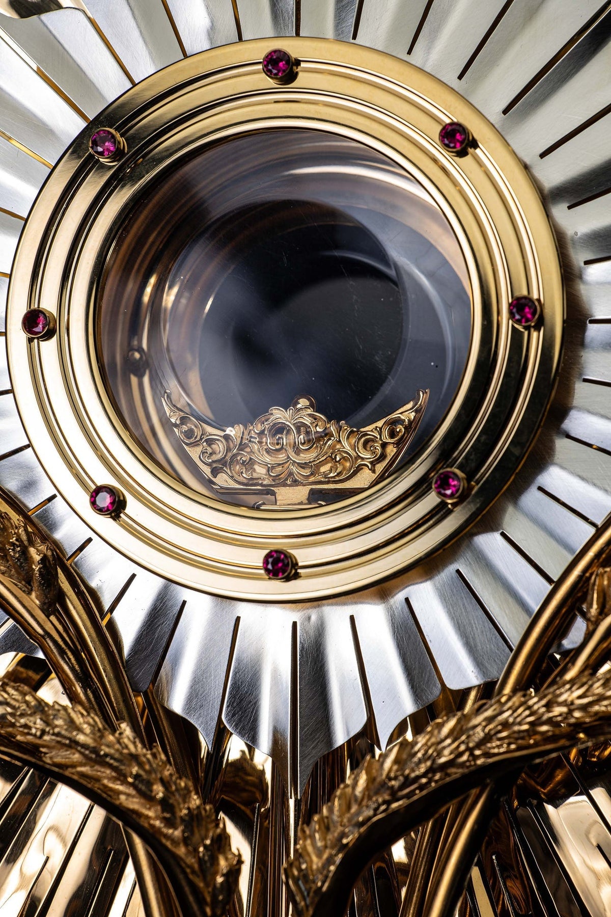 Close-up of gilded brass monstrance showing the clear host case and ornate lower relief