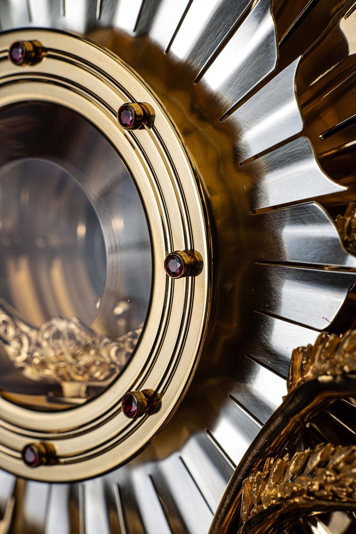Side detail of gilded brass monstrance with ruby settings and silver-toned sunburst rays