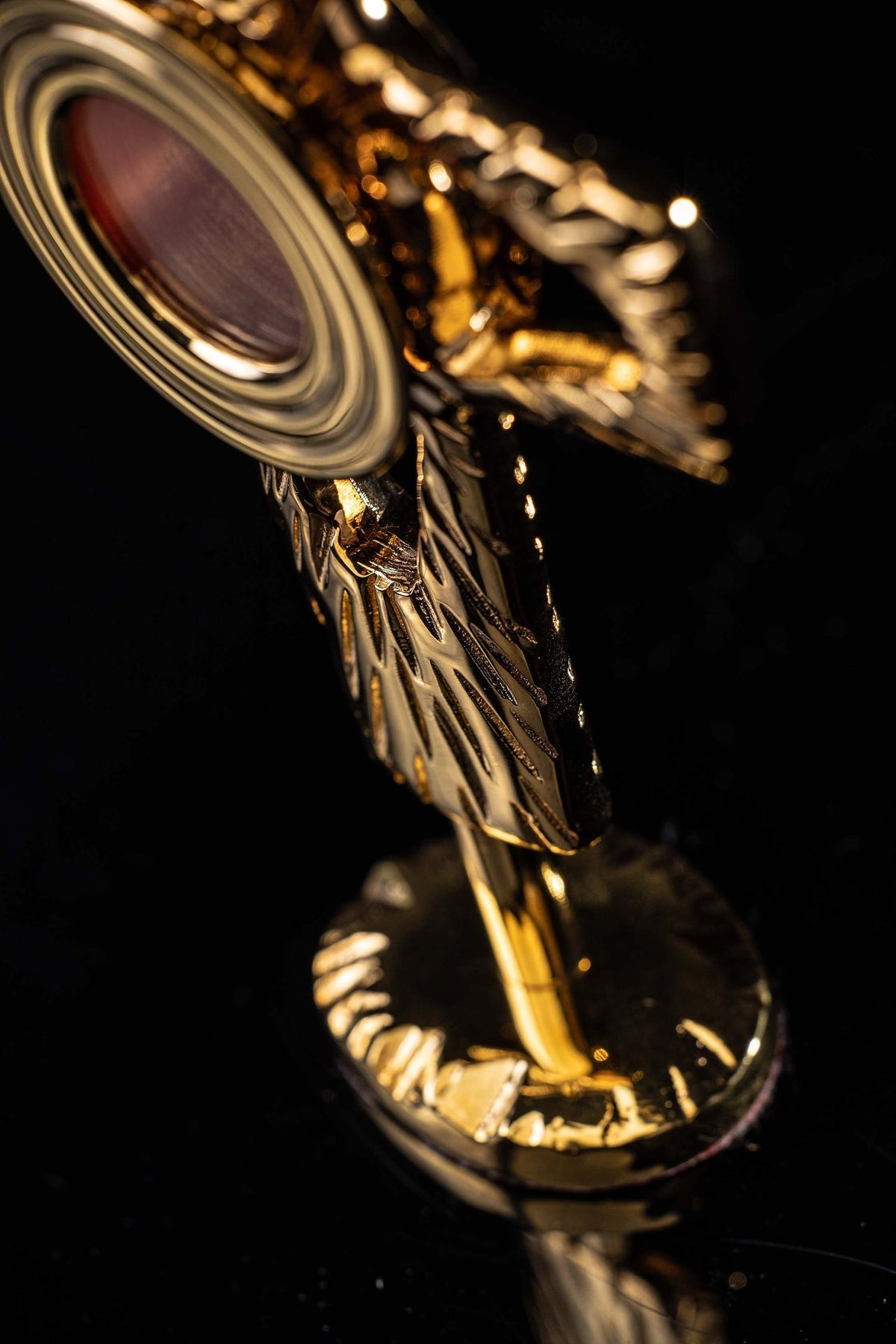 Side detail of brass reliquary showing circular frame and engraved cross arms