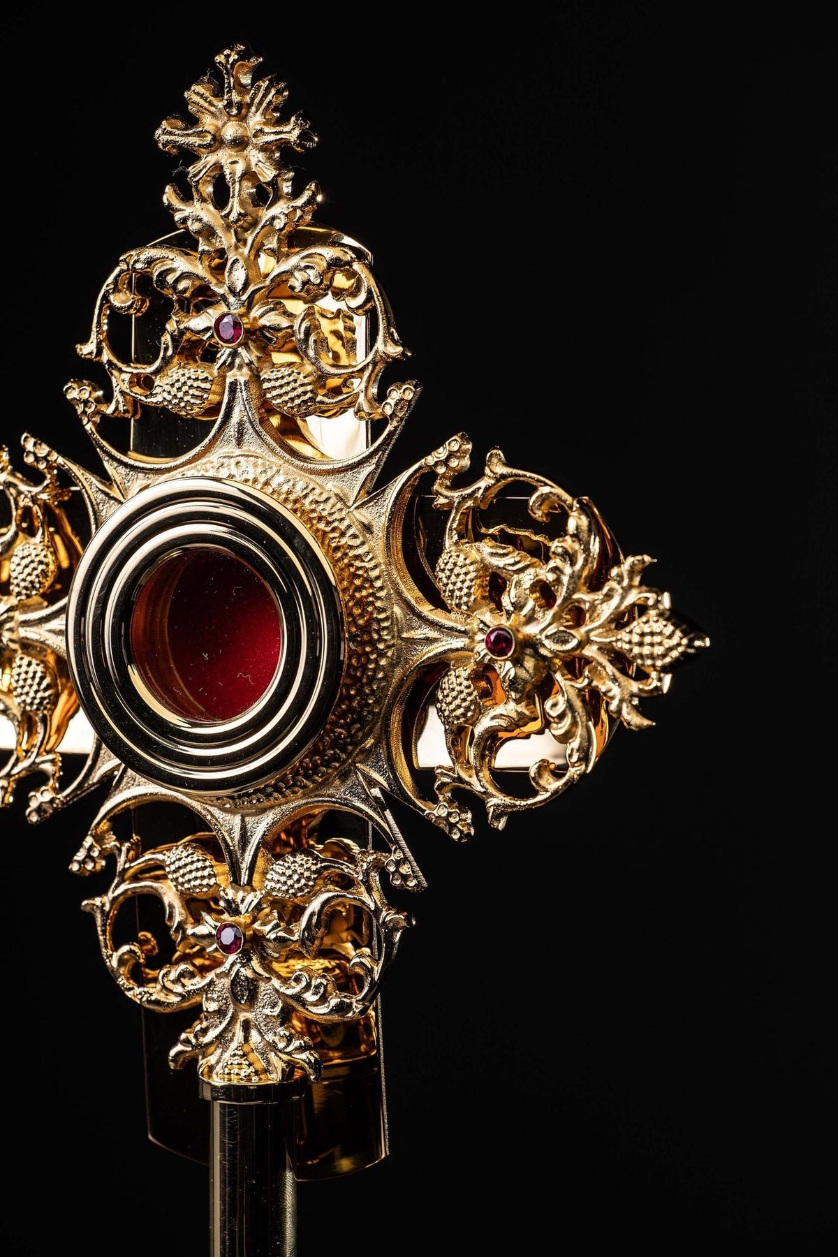 Angled close-up of gilded brass reliquary with round luna and floral scrollwork