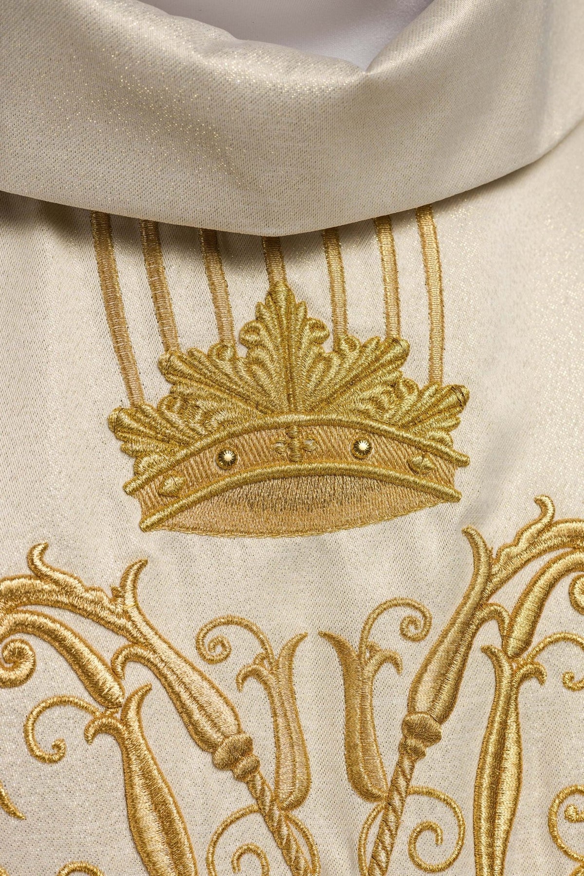 Detail view of the chasuble's ecru fabric and gold vertical embroidery