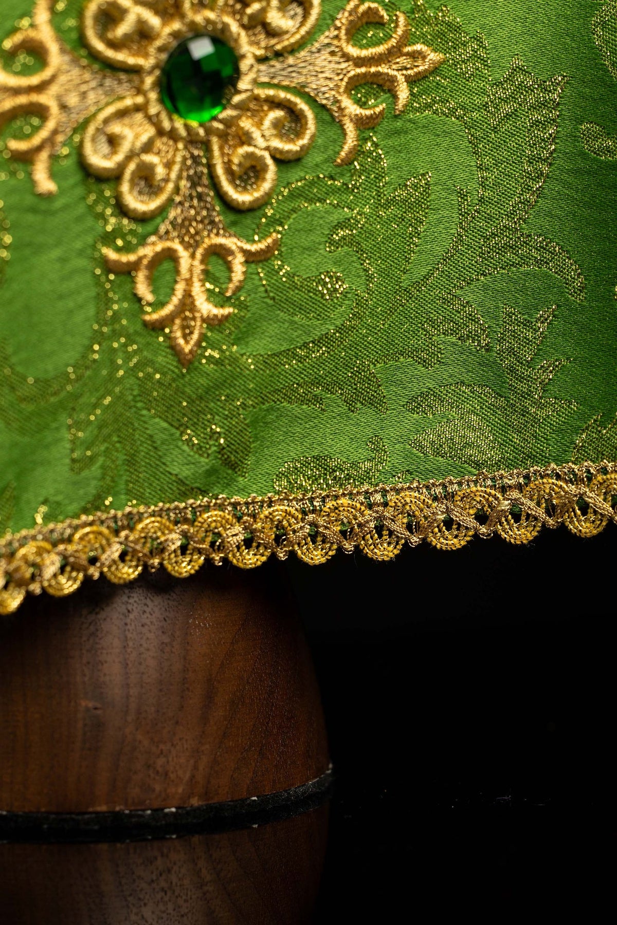 Trim detail of the green chalice veil with embroidered gold cross and decorative stone