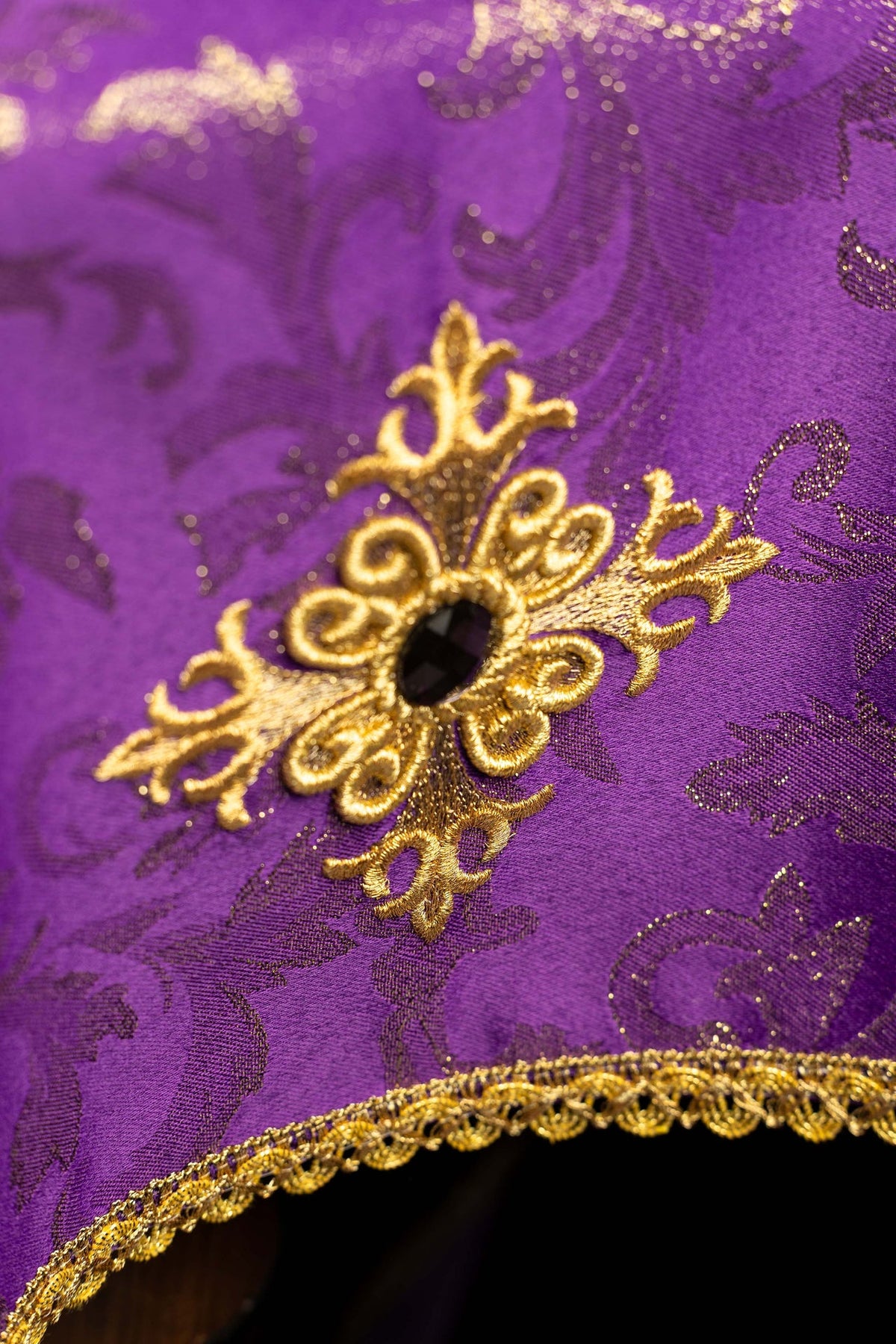 Close-up of the chalice veil showing embroidered gold cross, purple fabric and gold trim
