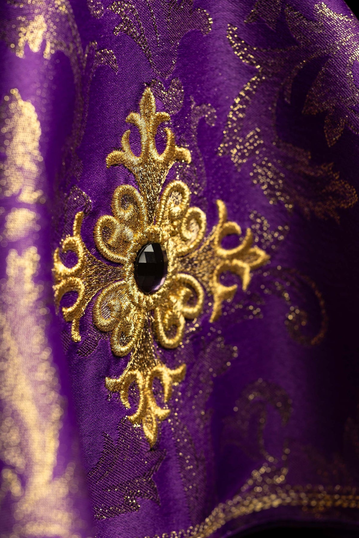 Close-up of the purple ciborium veil showing embroidered gold cross and dark stone