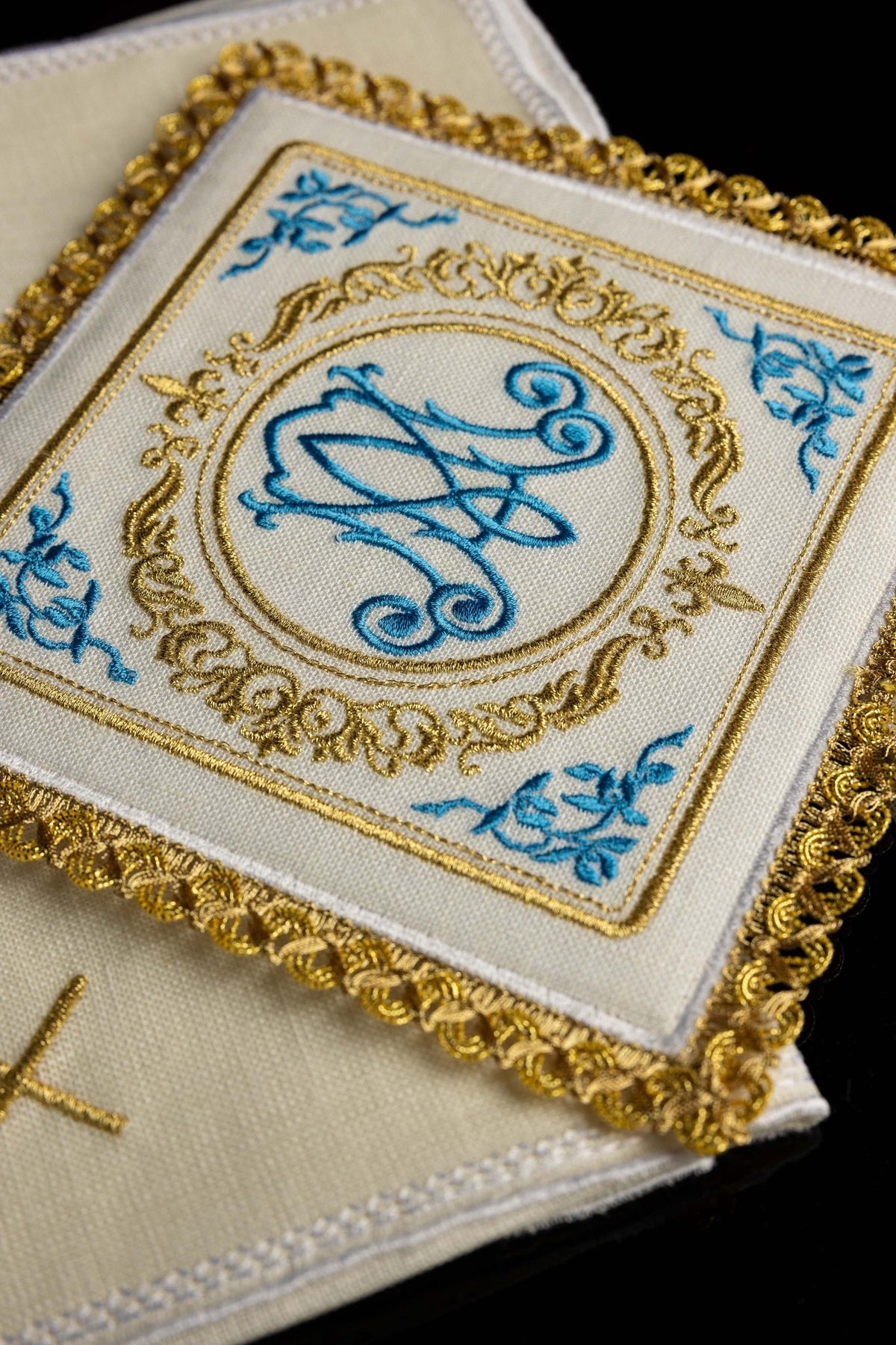 Angled close-up of Marian altar linens set with blue floral motifs and gold Marian embroidery